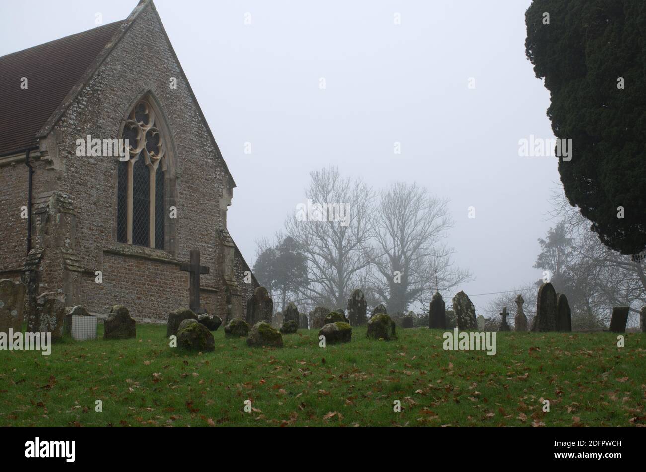 St. George's Church Gebäude und Friedhof an einem nebligen Tag im Winter, Crowhurst, Sussex, England, Großbritannien Stockfoto