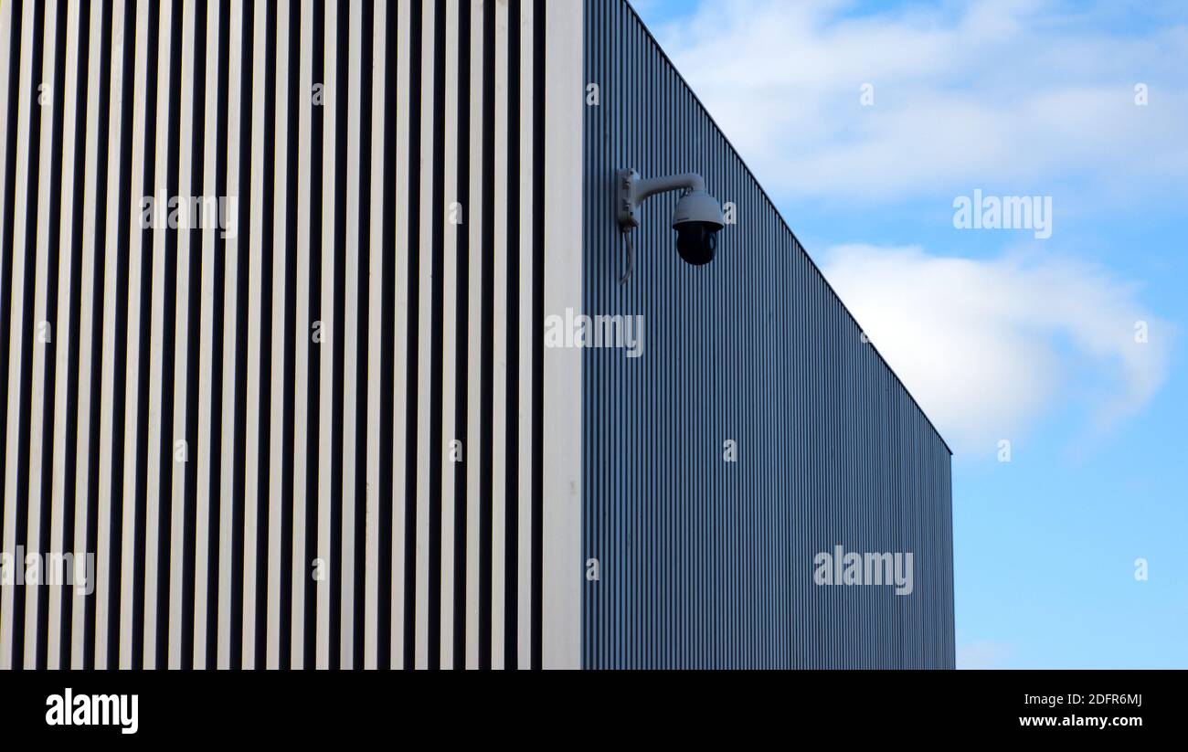 Eine Sicherheitskamera an der Seite des Bexhill Museums mit einer Wand mit starken vertikalen Linien. Stockfoto