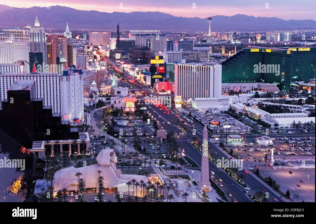 Ein Luftbild bei Sonnenuntergang zeigt die hellen Lichter der gehobenen Resort-Hotels und Casinos, die den Strip säumen, der der Spitzname für den weltberühmten 4.3 Meilen (6.8 Kilometer) Abschnitt des lebhaften Las Vegas Boulevard in Las Vegas, Nevada, USA ist. Dieses berüchtigte Wüstenziel, das für seine Glücksspiele und seine guten Zeiten bekannt ist, wurde in den 1940er Jahren mit seinem ersten Hotel/Casinos entlang des Strip zum Leben erweckt. In diesen Tagen leuchten elektronische Werbetafeln Tag und Nacht in Themenresorts, die ihre opulenten Showrooms mit namensreicher Unterhaltung annoncieren, die helfen, Millionen von Touristen jährlich nach Las Vegas anzuziehen. Stockfoto