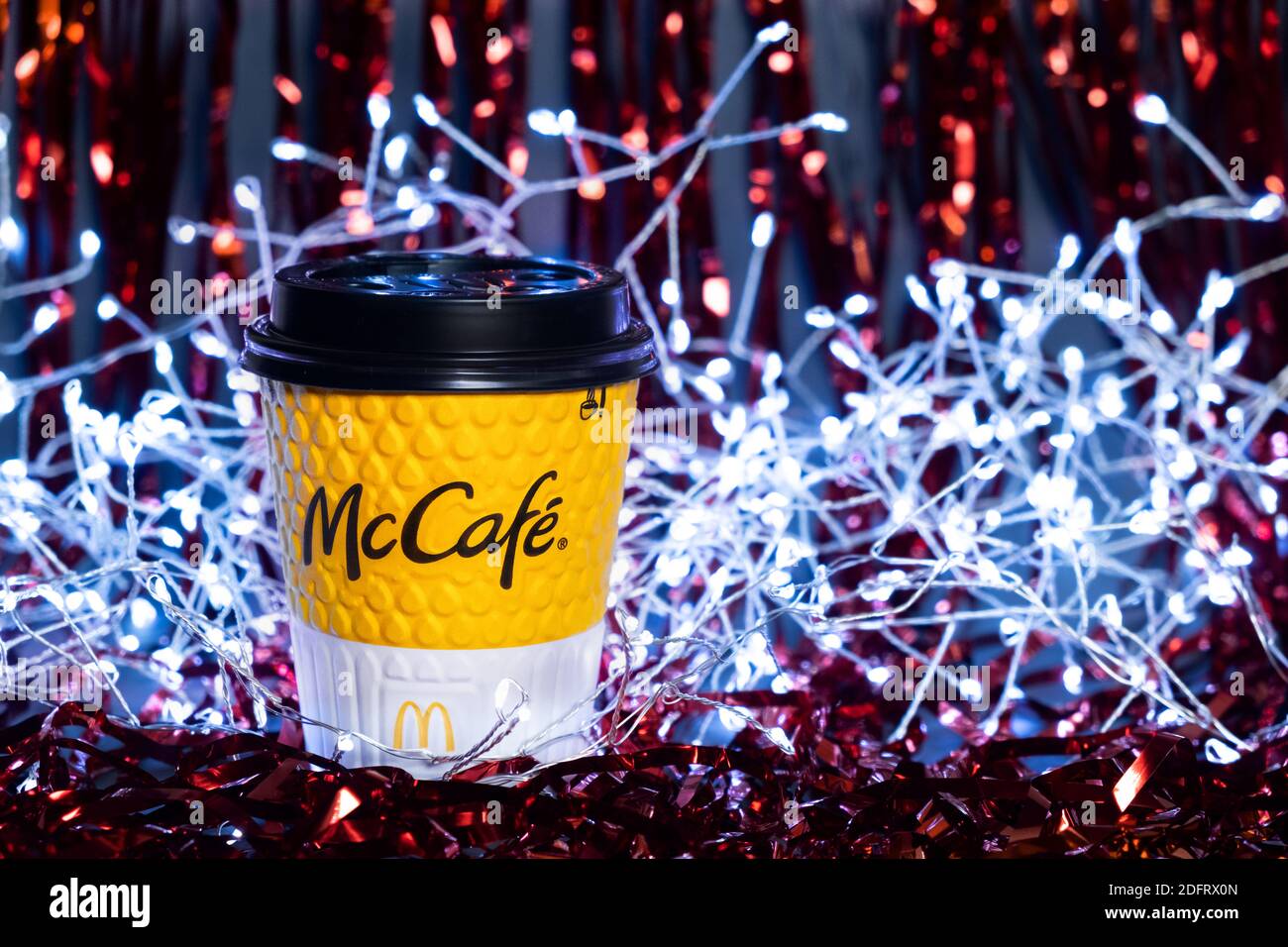 Gelbe McCafe Tasse auf einem festlichen Neujahrshintergrund. Rote Lametta und Girlande im Hintergrund. Kiew, Ukraine, 6. Dezember 2020 Stockfoto