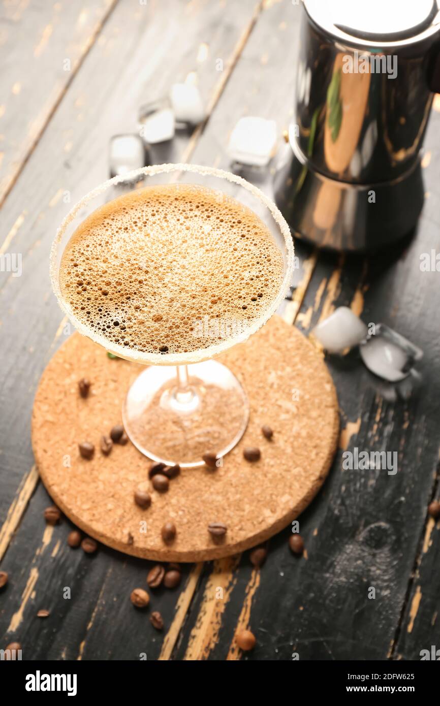Ein Glas leckerer Espresso martini-Cocktail und eine Geysir-Kaffeemaschine Auf Holzhintergrund Stockfoto
