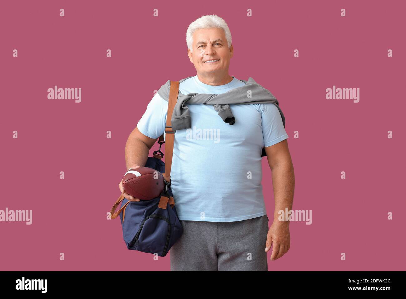 Sportlicher Senior mit Tasche und Rugby Ball in Farbe Hintergrund Stockfoto