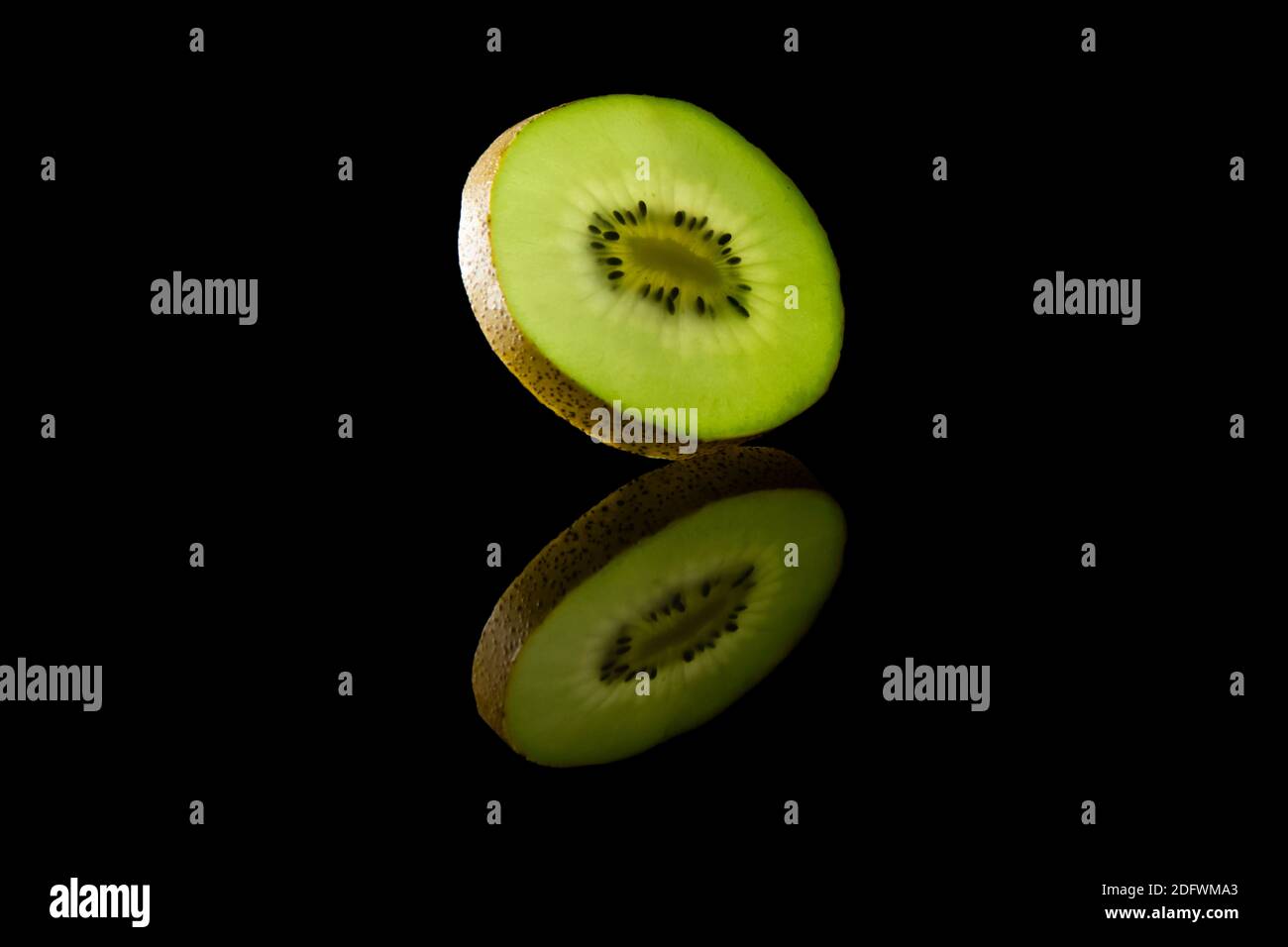 Scheibe grüne Kiwi-Frucht vor schwarzem Hintergrund Stockfoto