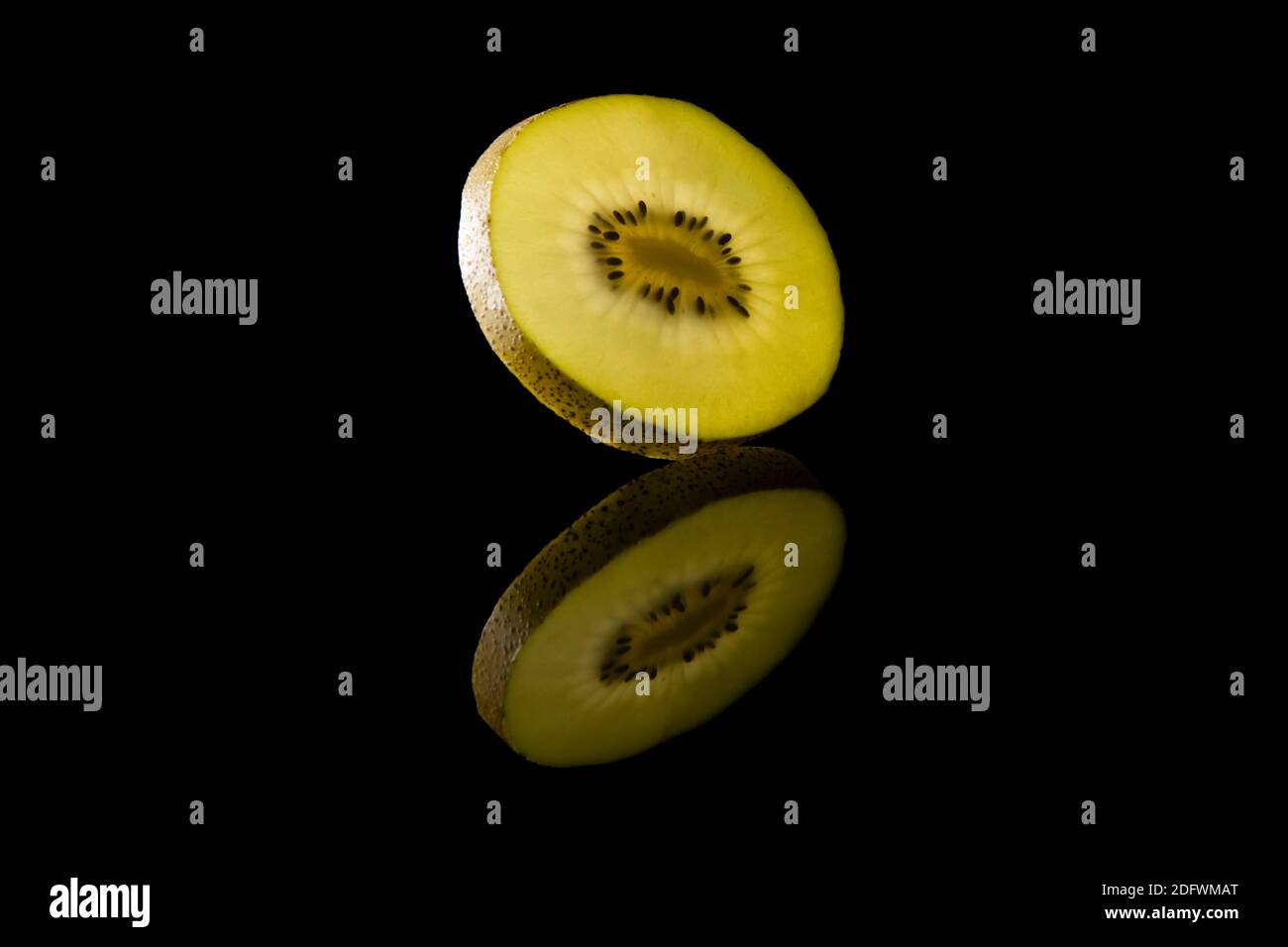 Scheibe gelber Kiwi-Früchte vor schwarzem Hintergrund Stockfoto
