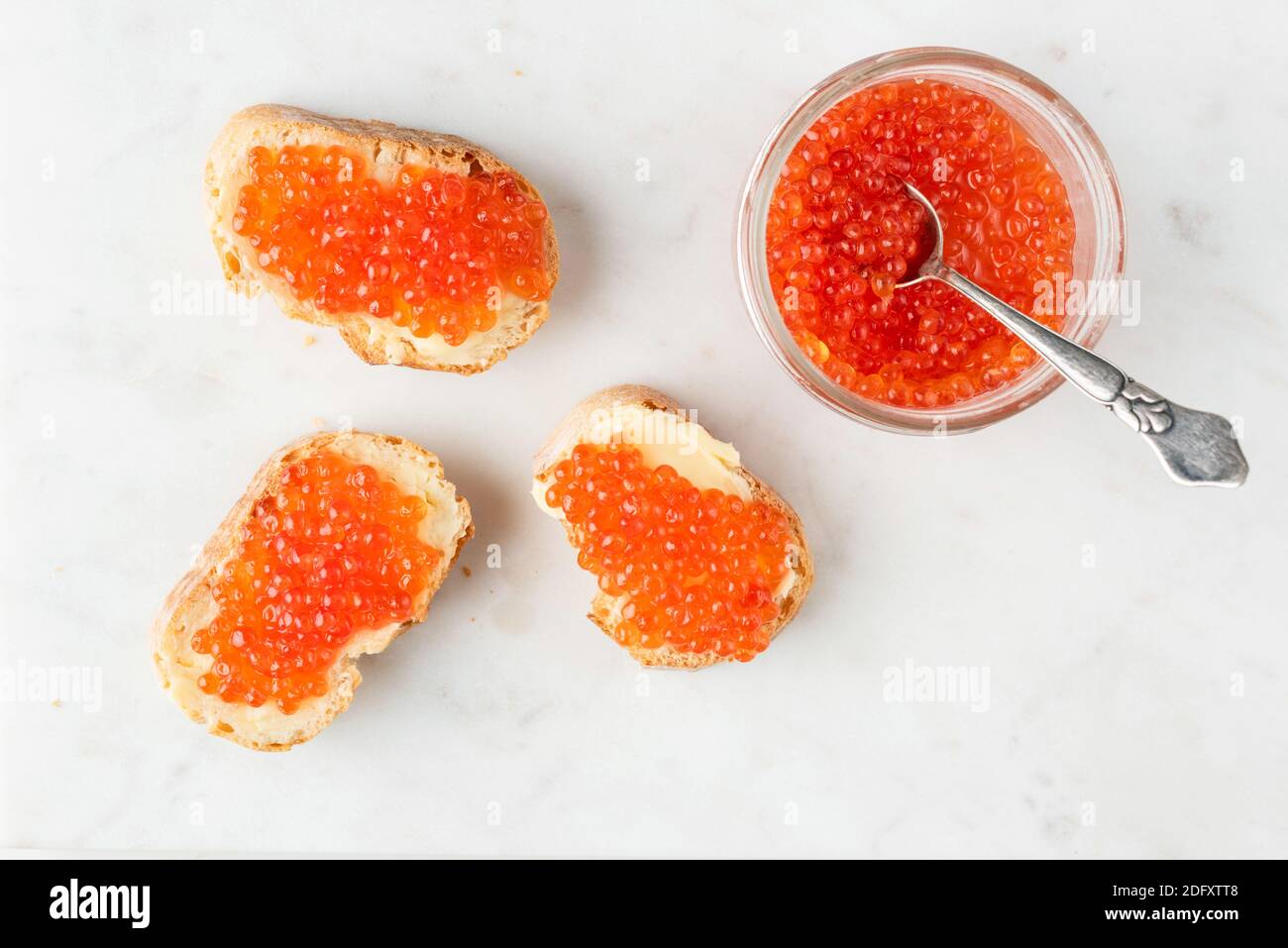 Roter Kaviar und Butter kanappen auf Baguette Toast Brot, weißer Marmor Hintergrund. Traditionelle russische Vorspeise zu Weihnachten, Neujahrstisch Stockfoto