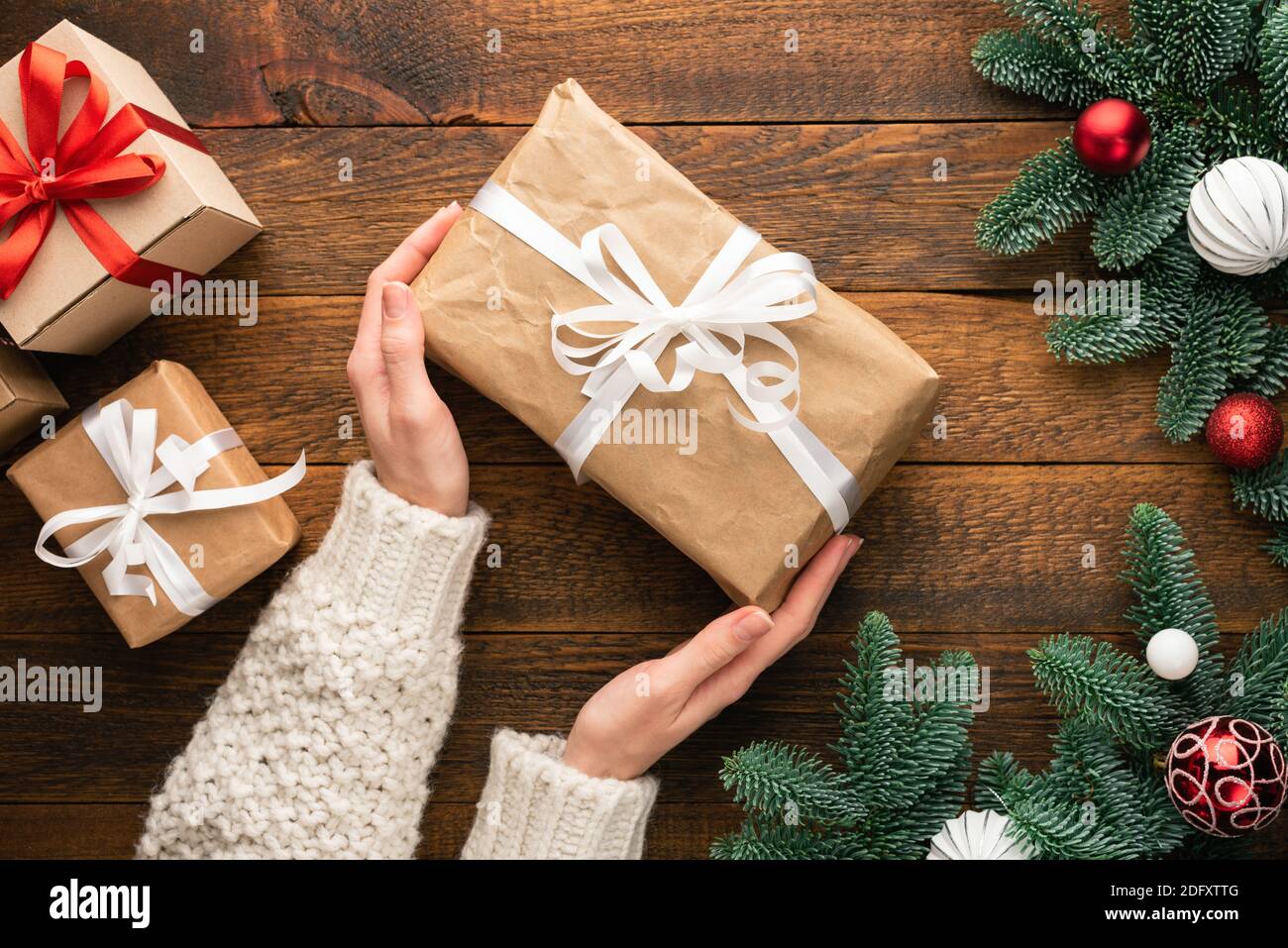 Weihnachtsgeschenke auf Holzhintergrund in weiblichen Händen. Draufsicht Stockfoto