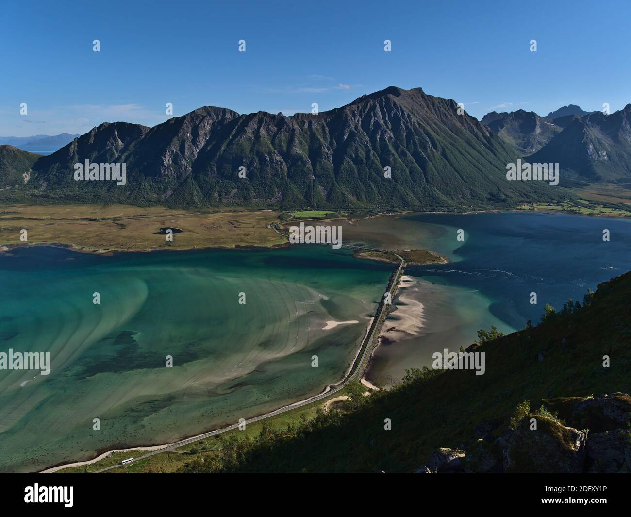 Atemberaubender Panoramablick auf Fjord Grunnførfjorden mit Straßendamm und türkisfarbenem seichtem Wasser und Bergen im Hintergrund am sonnigen Sommertag. Stockfoto