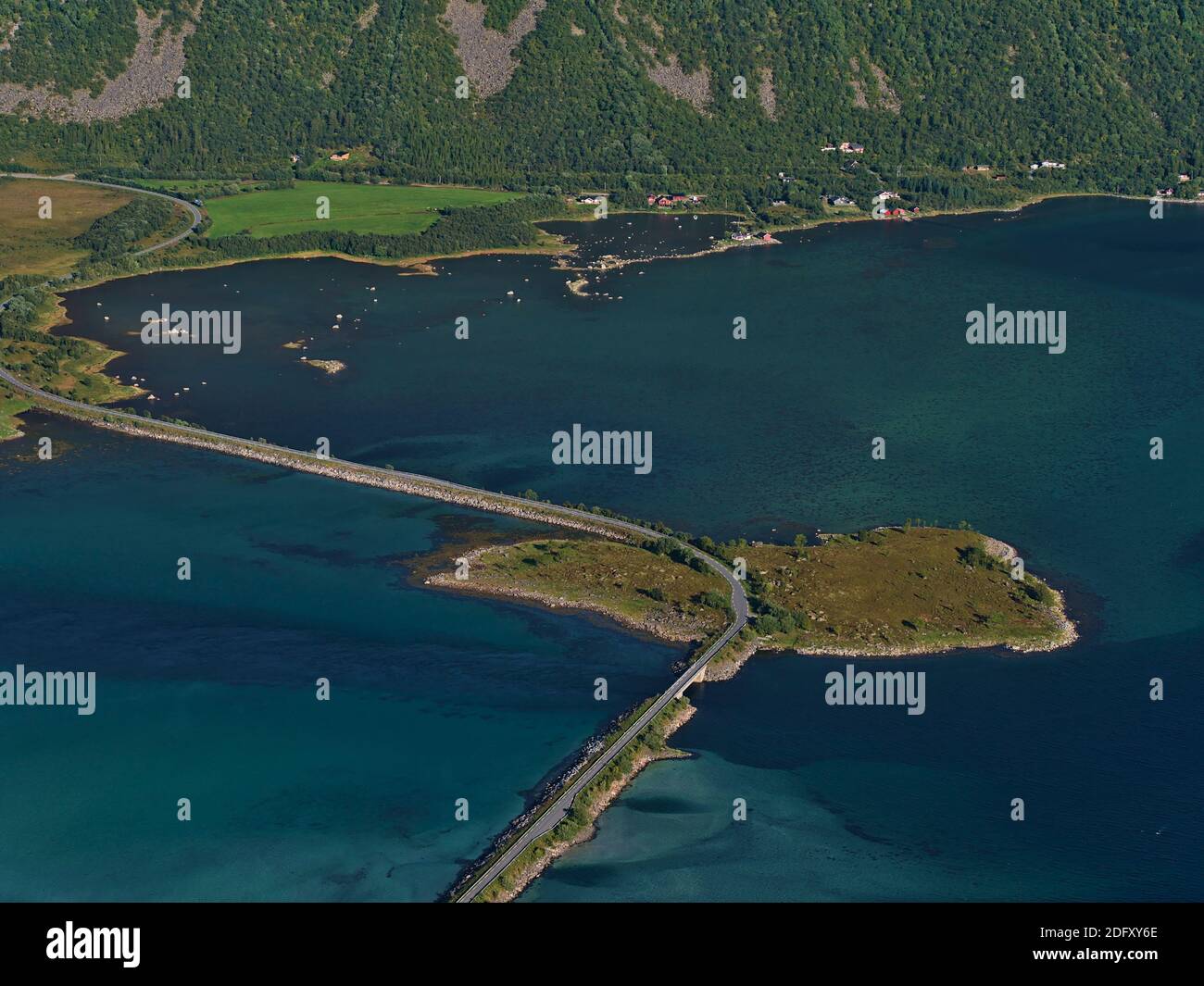 Schöne Luftaufnahme des Fjords Grunnførfjorden mit Straßendamm und kleiner Insel Storholmen umgeben von türkisfarbenem und blauem seichtem Wasser. Stockfoto