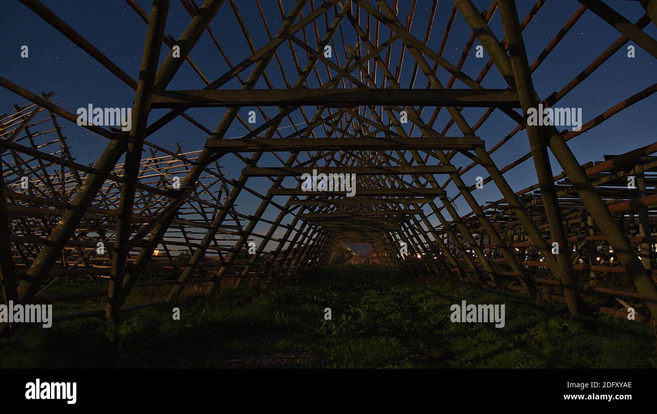 Nachtansicht der dreieckig geformten hölzernen Trockengestelle für die Erhaltung der traditionellen Stockfisch mit Sternen auf dem blauen Himmel im Hafen von Svolvaer verwendet. Stockfoto