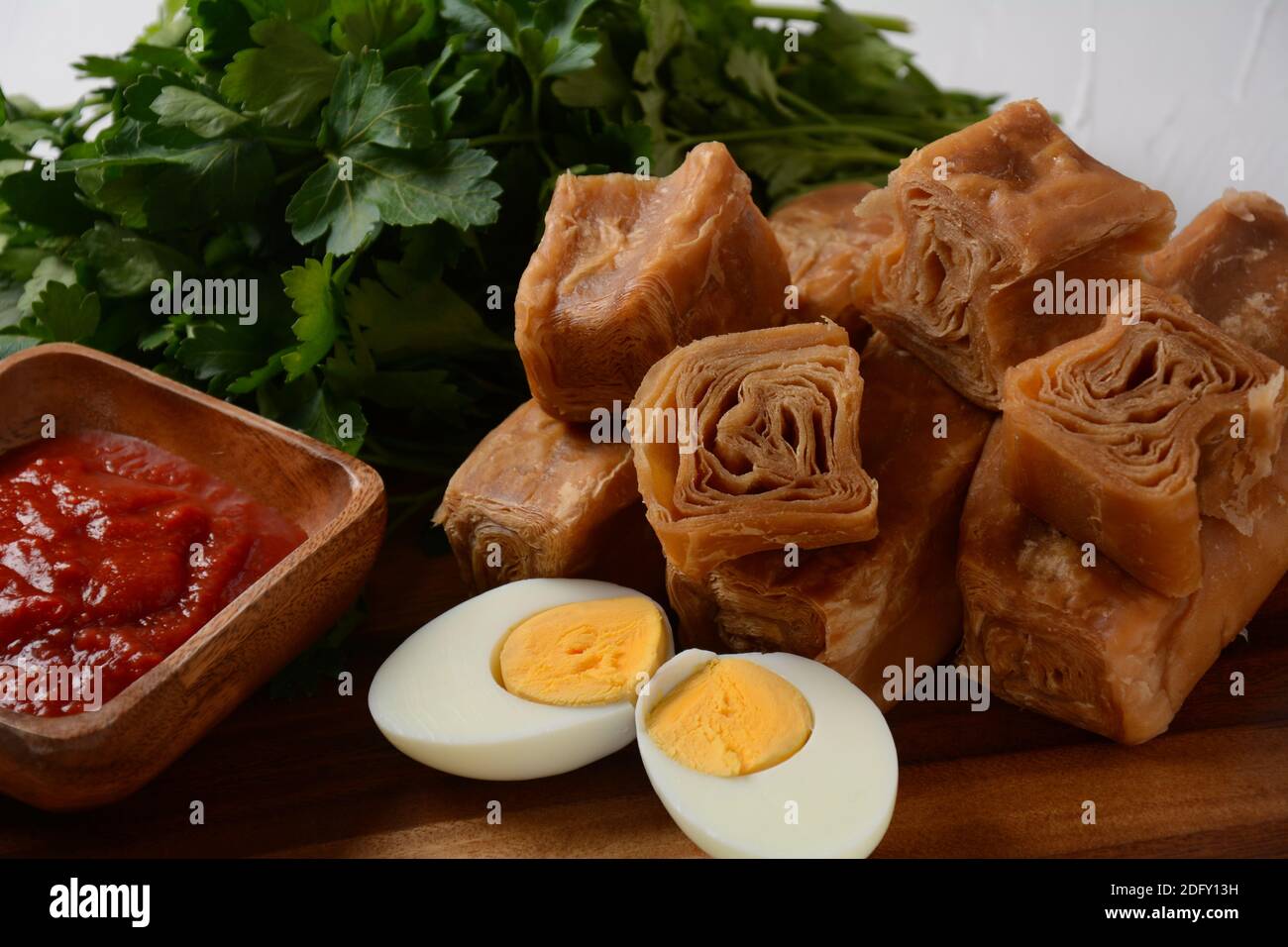 Jachnun oder Jahnun, jemenitisches jüdisches Gebäck, serviert mit frisch geriebenen Tomaten und gekochtem Ei und Zhug, aus den Adeni-Juden, und traditionell Stockfoto