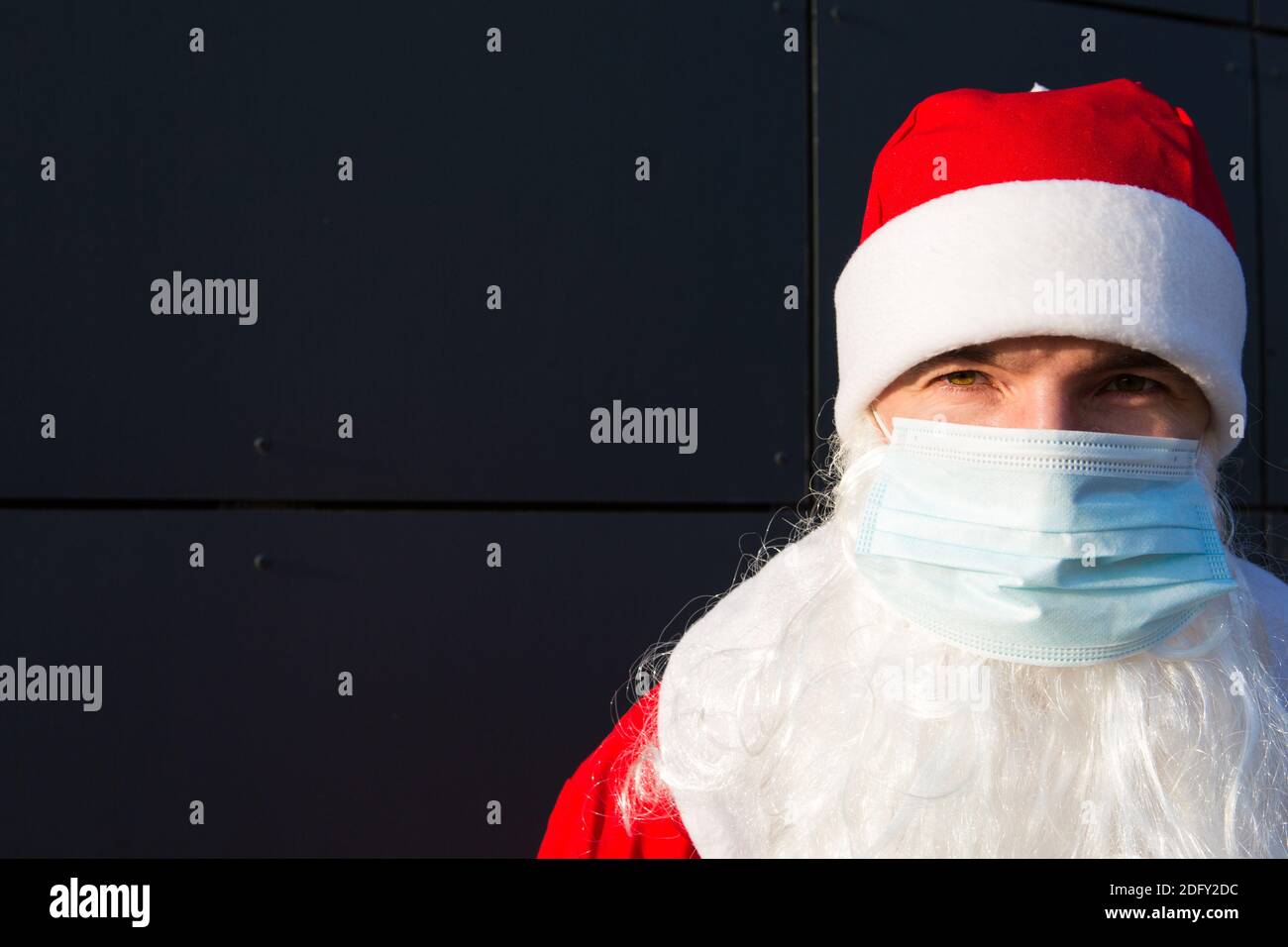 Weihnachtsmann mit weißem Bart in rotem Mantel in einer medizinischen Maske. Weihnachten in der Coronavirus-Pandemie, saisonale Krankheiten, SARS und Lungenentzündung in der Holida Stockfoto