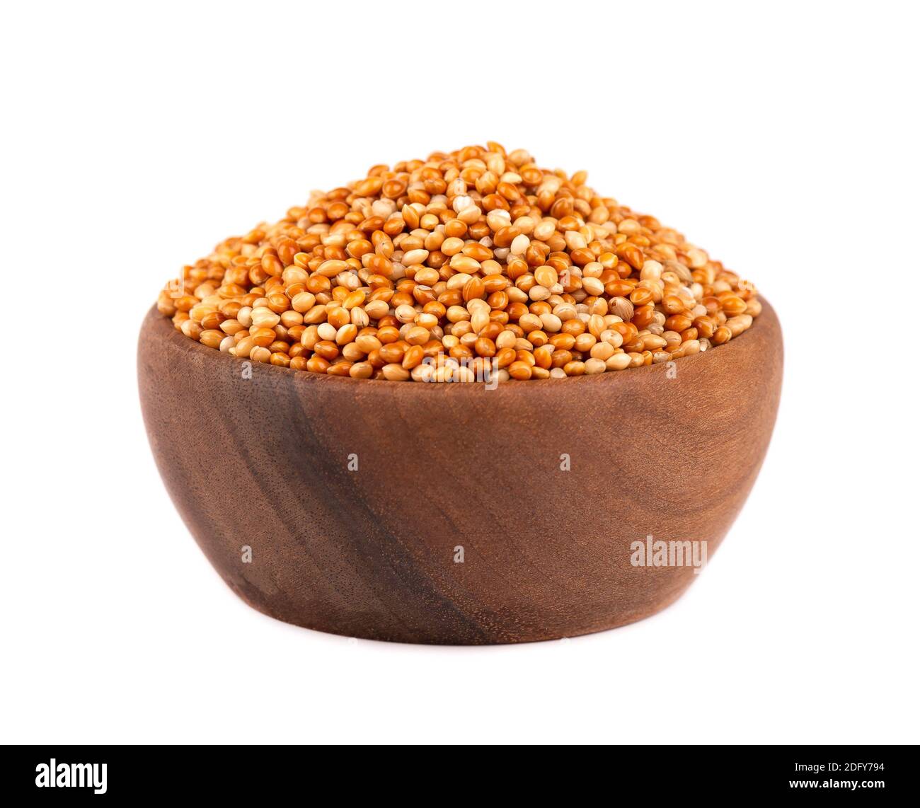 Hirse in Holzschale, isoliert auf weißem Hintergrund. Ungeschälte Hirsekerne. Stockfoto