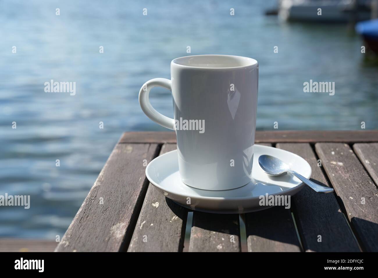 Kaffeebecher auf einem Tisch direkt am Wasser, Kopierbereich, ausgewählter Fokus, enge Schärfentiefe Stockfoto