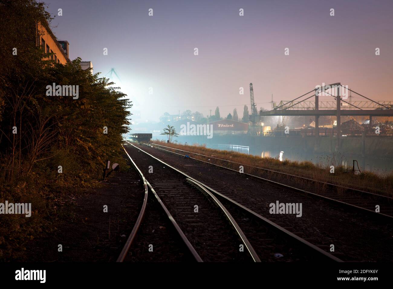 Gleise und Ladekran bei Nacht im Rheinhafen im Stadtteil Deutz, Köln, Deutschland. Stockfoto