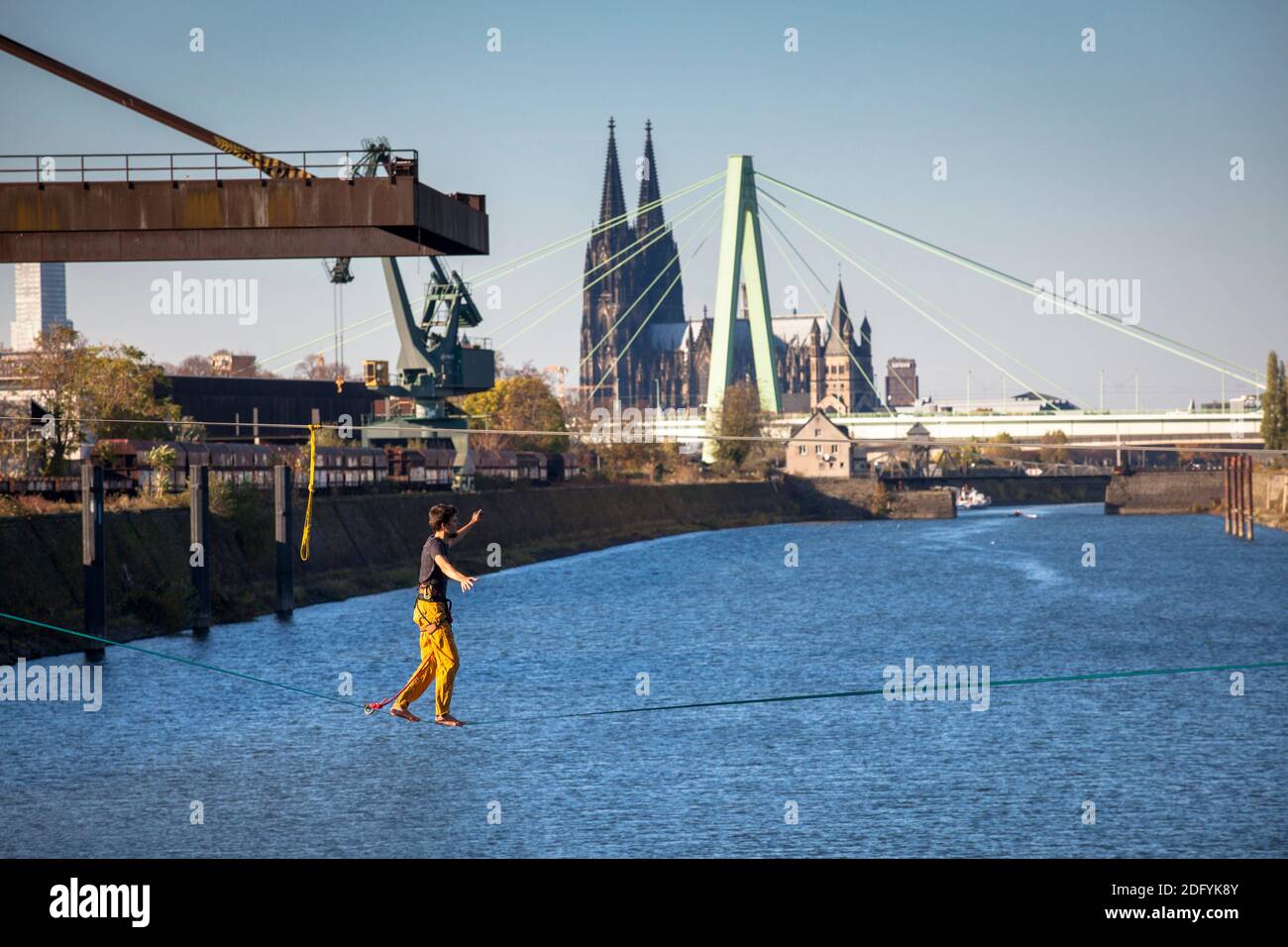 Mann auf Slackline im Rheinhafen im Stadtteil Deutz, im Hintergrund Dom und Severins Brücke, Köln, Deutschland. Stockfoto