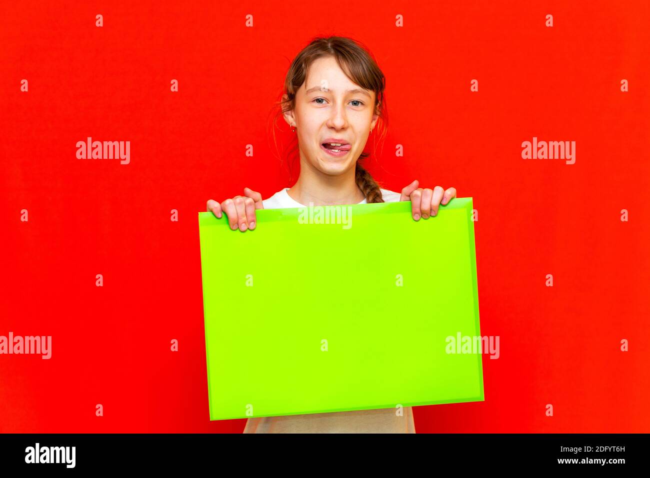 Junge selbstzufriedene Teenager Mädchen mit leerem Papier Blatt über roten Studio Hintergrund. Stockfoto