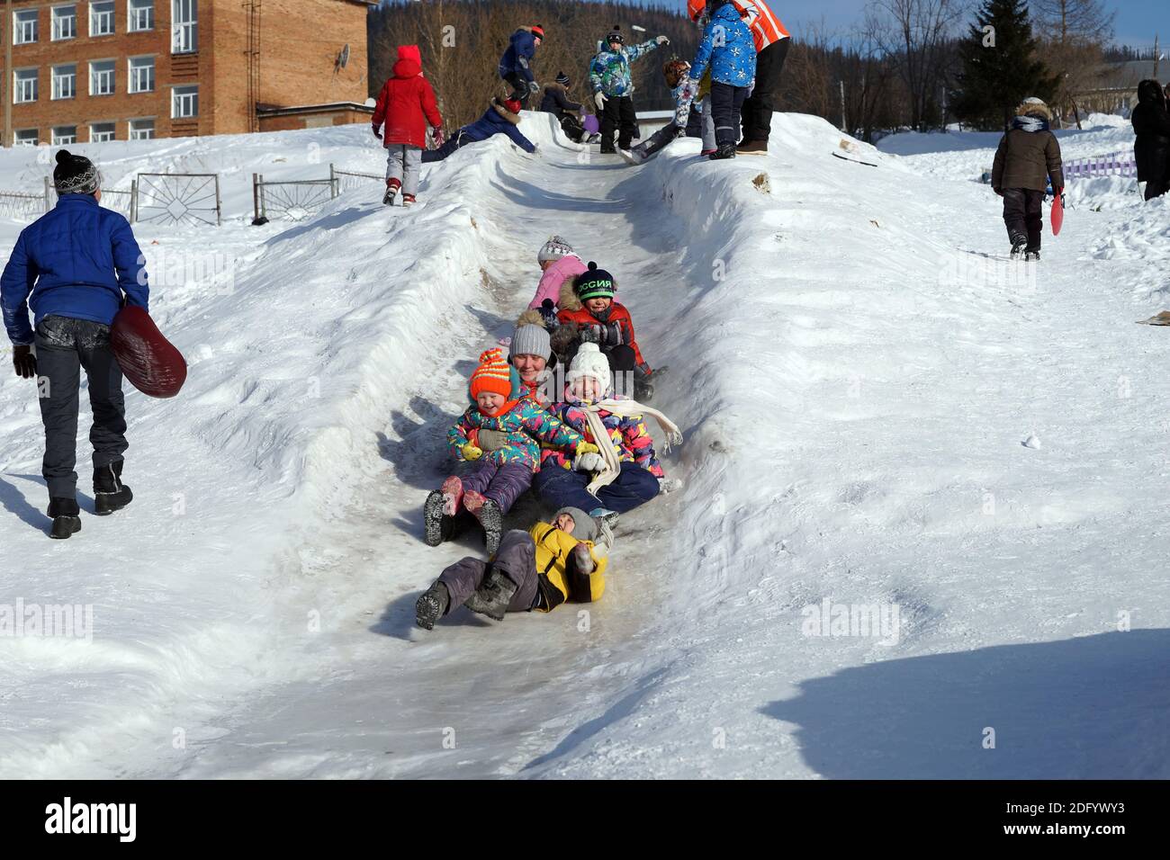 Glückliche Kinder reiten am Wochenende vom gefrorenen Hügel. Stockfoto