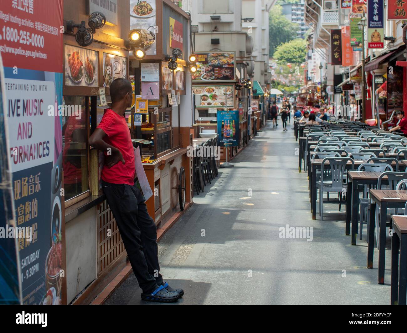 Ein Mann schaut auf leere Tische in einem Hawker Food Court im Zentrum von Singapur, Südostasien. Stockfoto