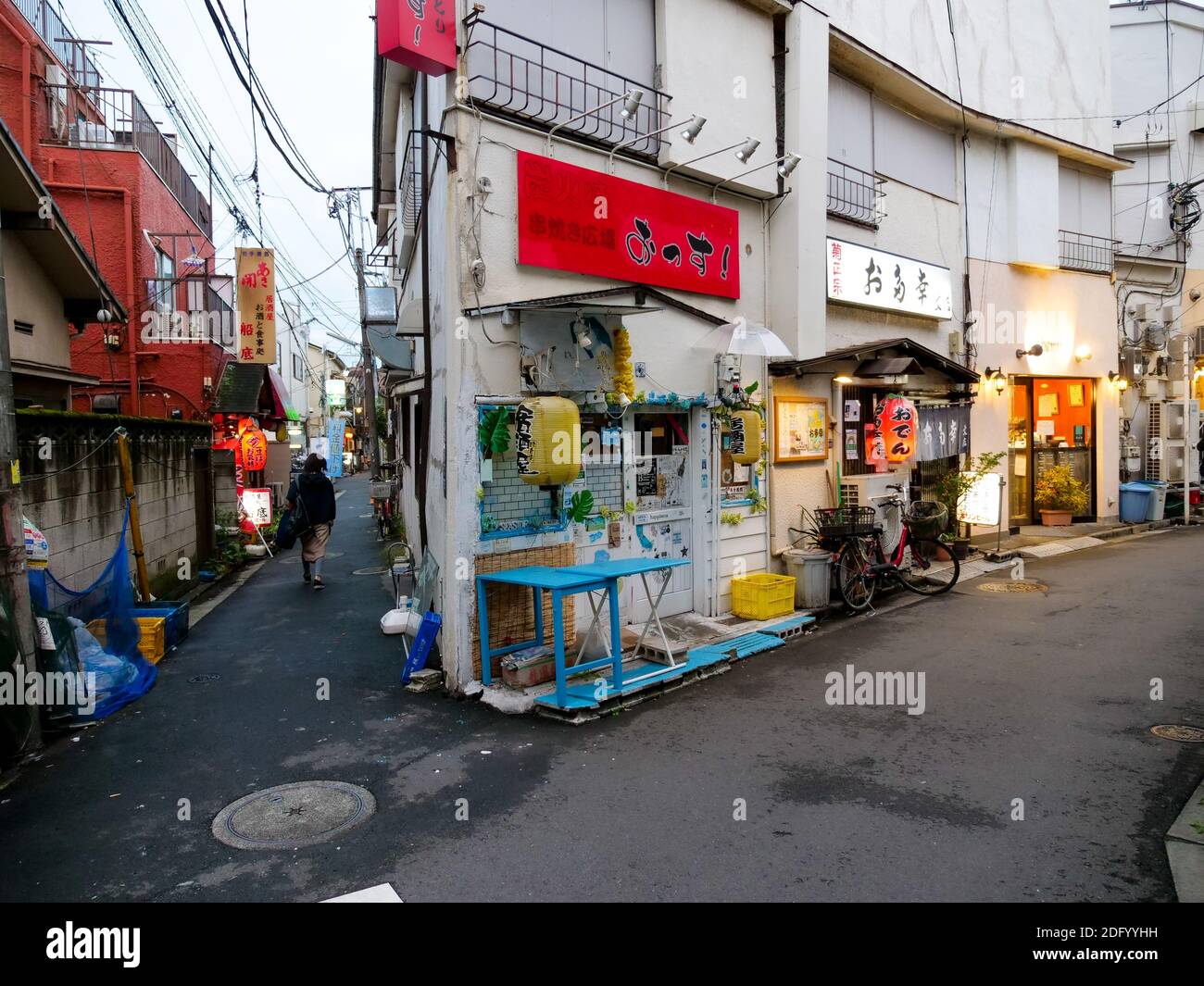 Ein Solist geht eine Gasse entlang, vorbei an Restaurants und Izakaya in Itabashi City, Tokyo. Stockfoto