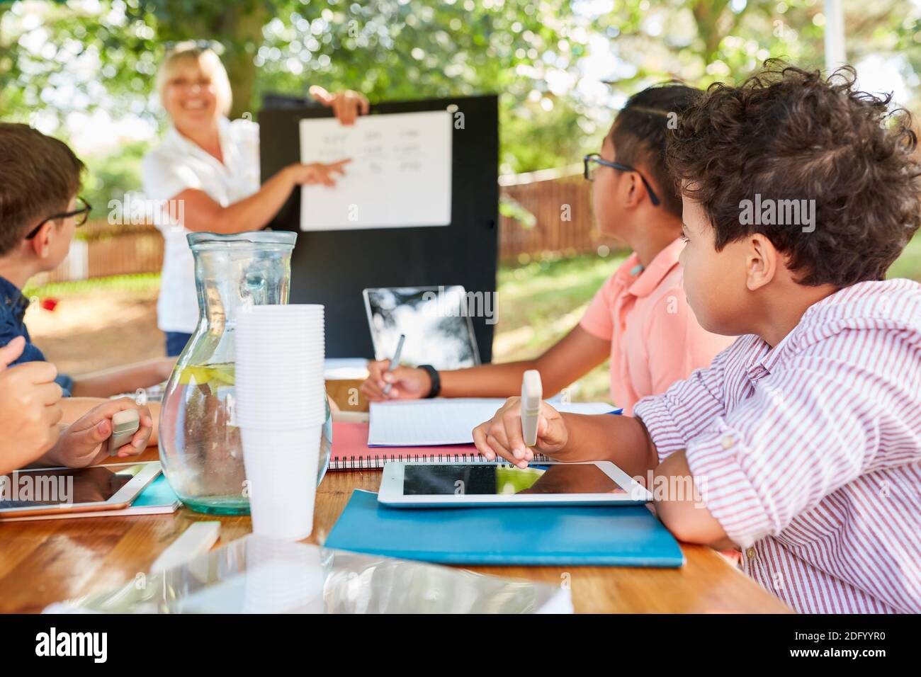 Frau als Lehrerin gibt Tutoring-Unterricht für Kinder in Der Sommer Schulferien Kurs Stockfoto