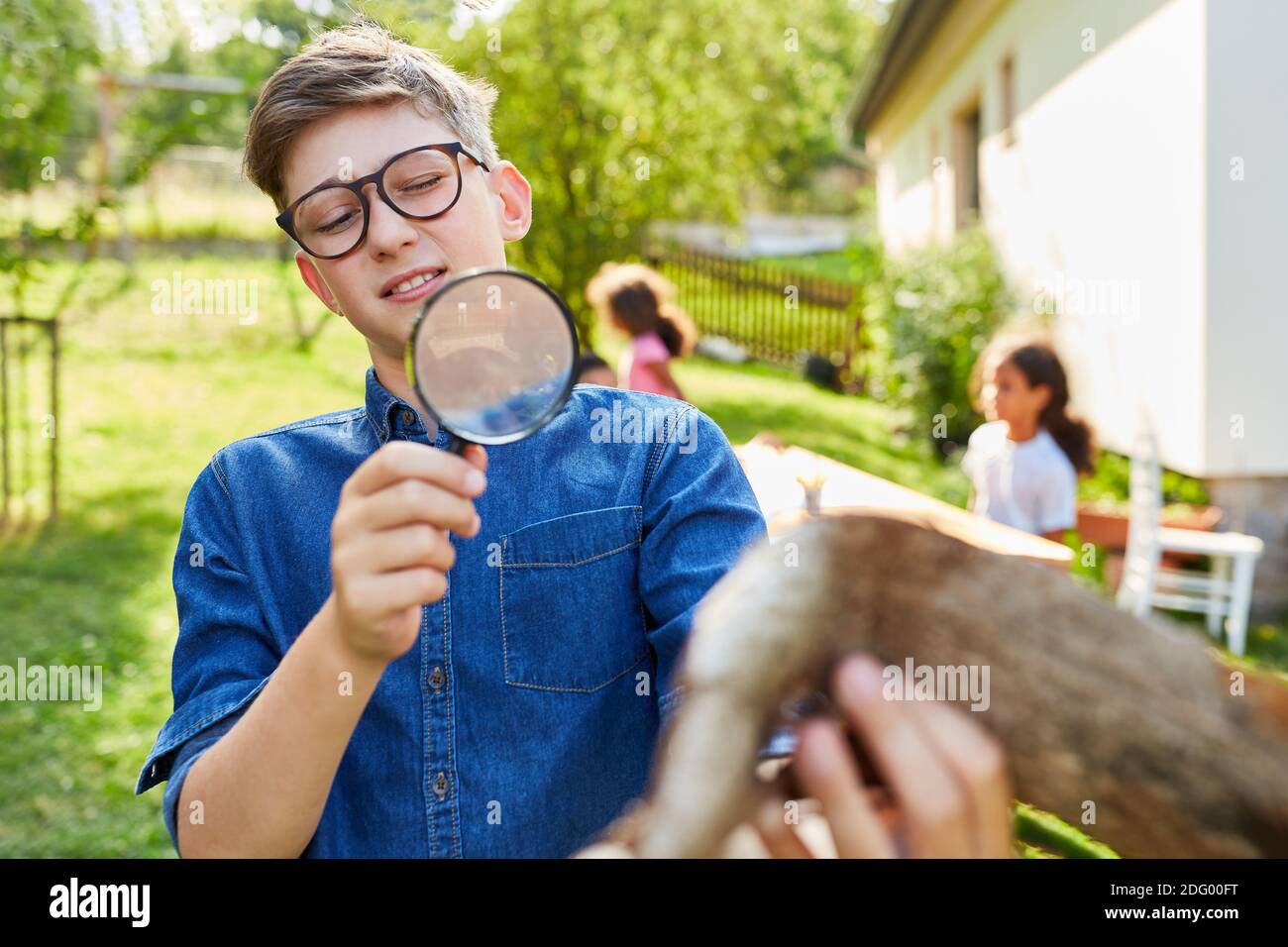 Junge als neugieriger Forscher im Biologieurlaub Sieht Baumrinde durch Vergrößerungsglas an Stockfoto