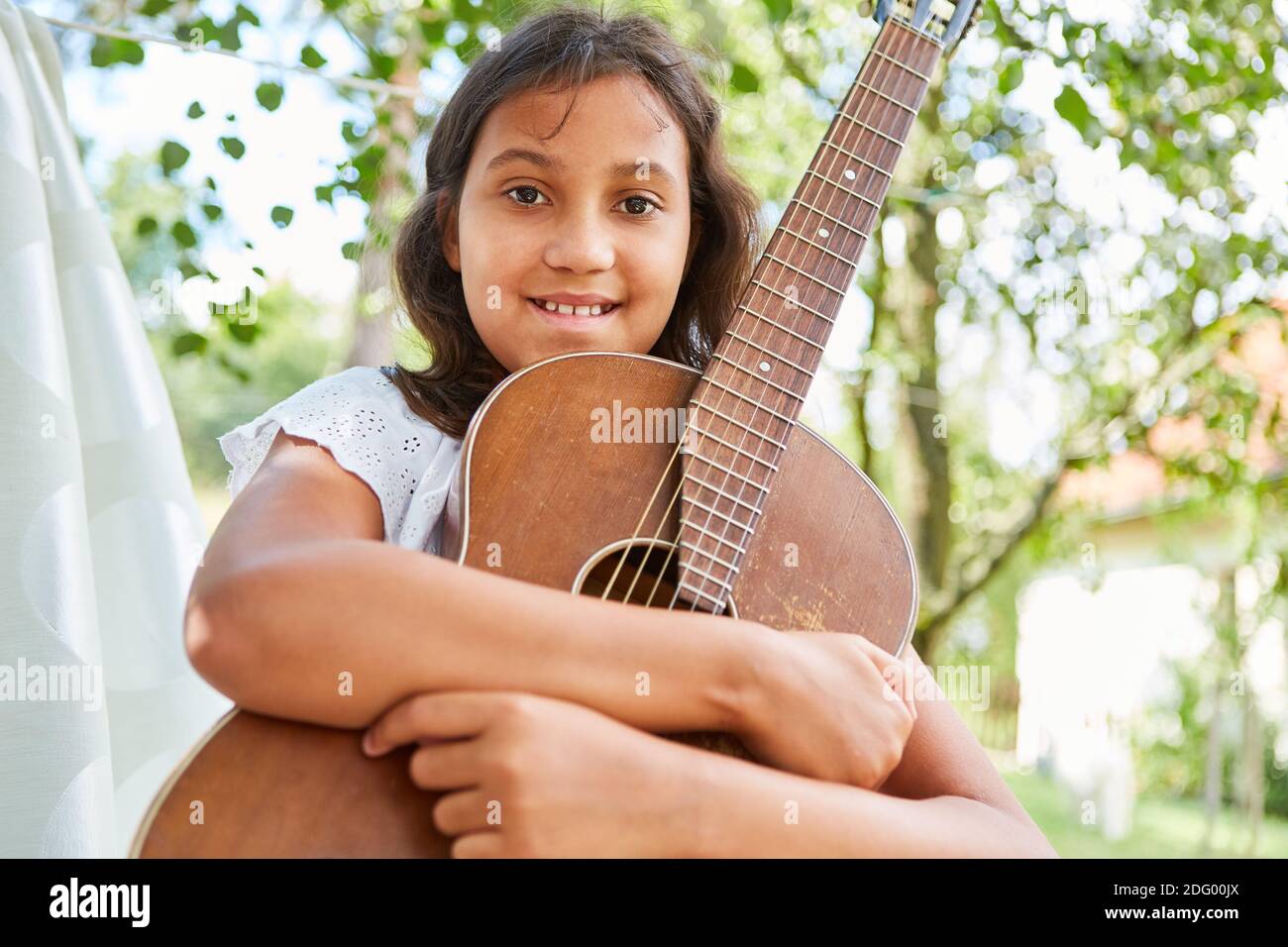 Fröhliches und stolzes Mädchen mit Gitarre als musikalisches Talent Im Sommercamp Stockfoto