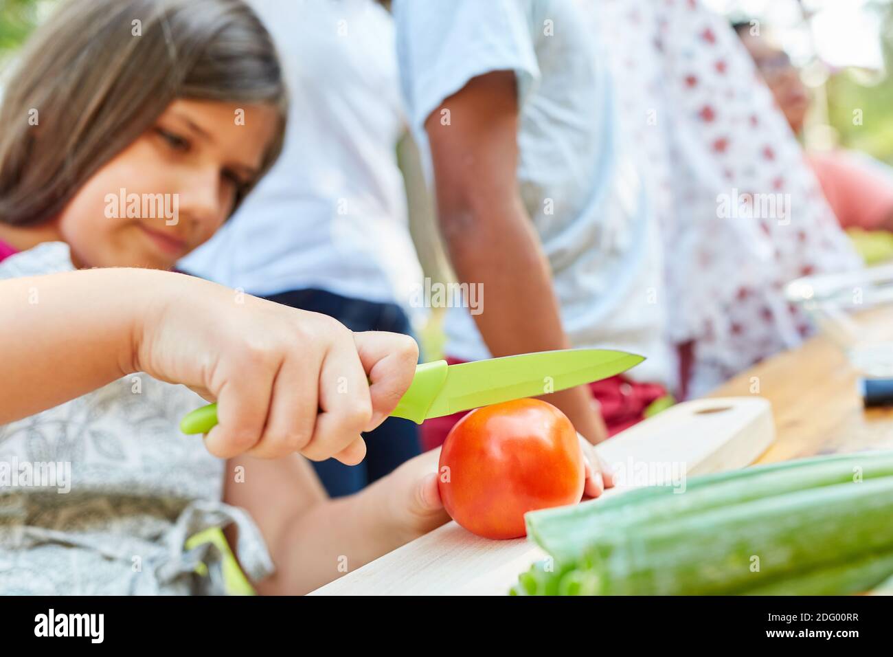 Kind schneiden Tomate in gesunden Kochkurs im Sommerlager Stockfoto