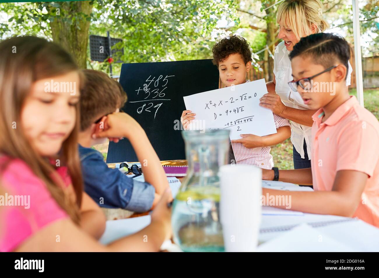 Tutoring Lehrer hilft Kindern mit Arithmetik in der Sommerschule Ferienkurs Stockfoto