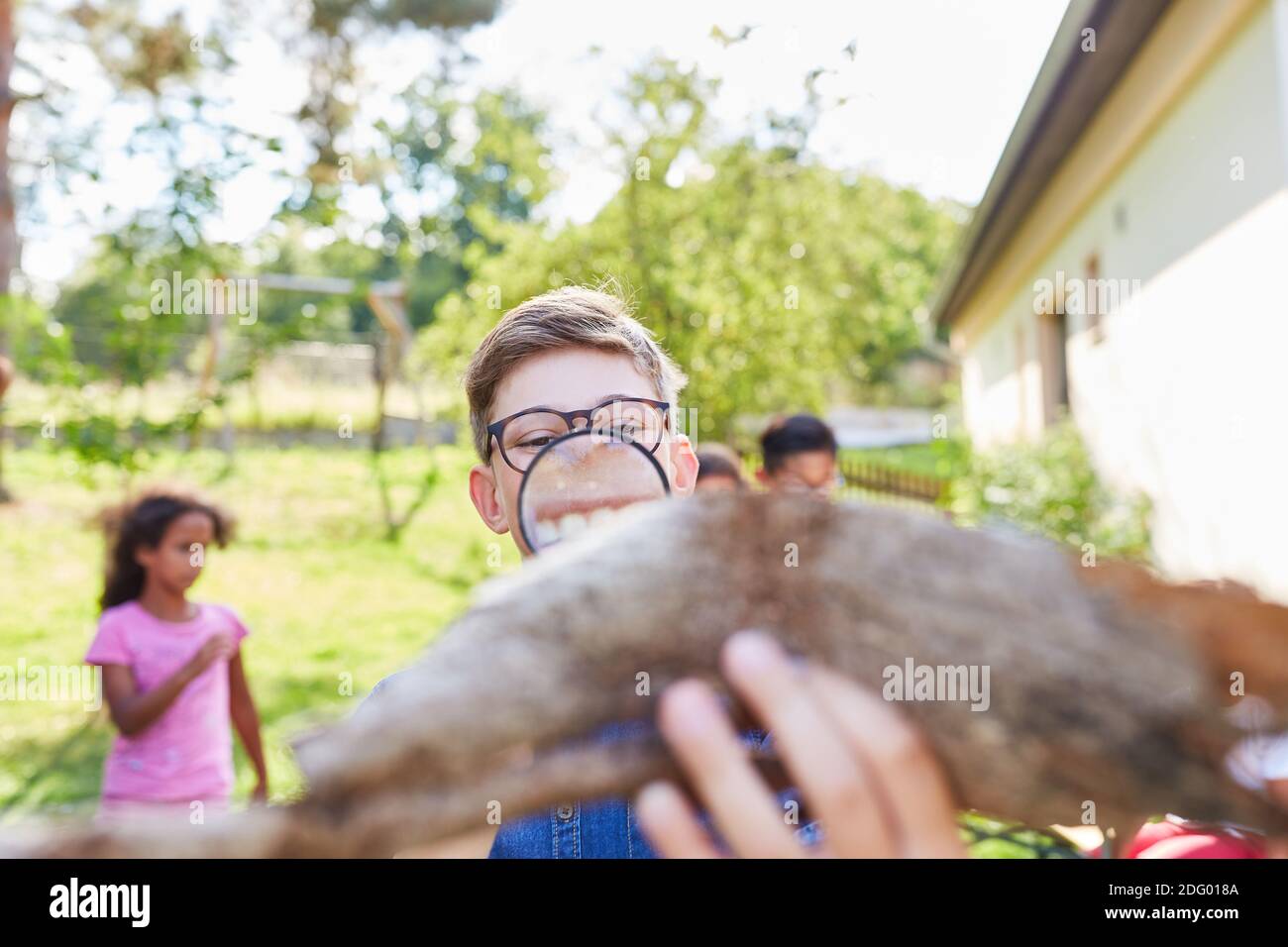 Kind sieht Baumrinde durch ein Vergrößerungsglas und Lernt über Biologie und Naturschutz Stockfoto