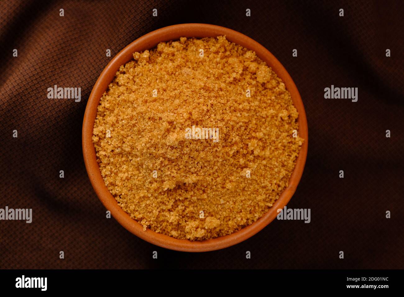 Brown Sugar Keramik Schüssel auf braunem Stoff Textur Hintergrund Stockfoto