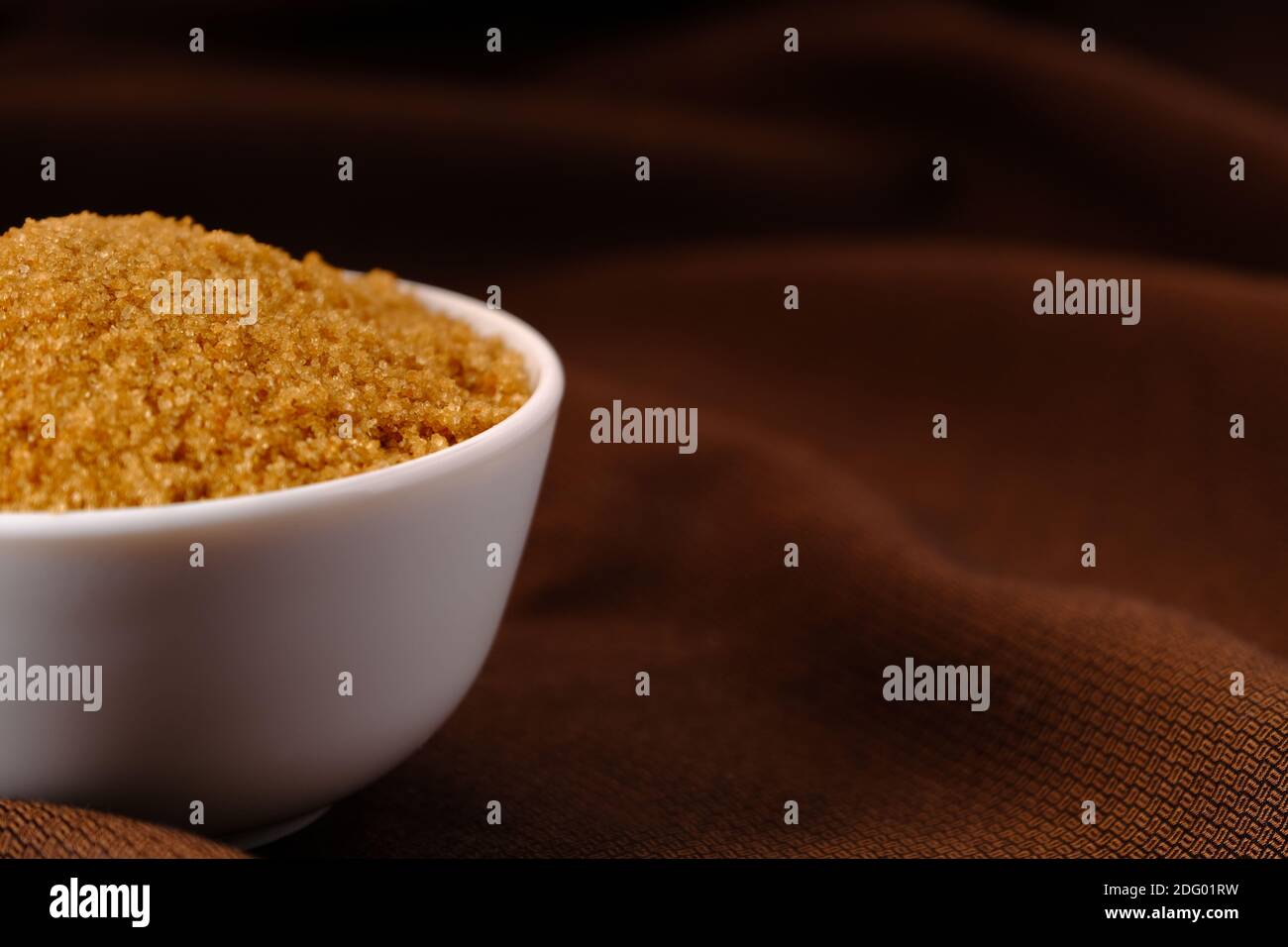 Brown Sugar Keramik Schüssel auf braunem Stoff Textur Hintergrund Stockfoto