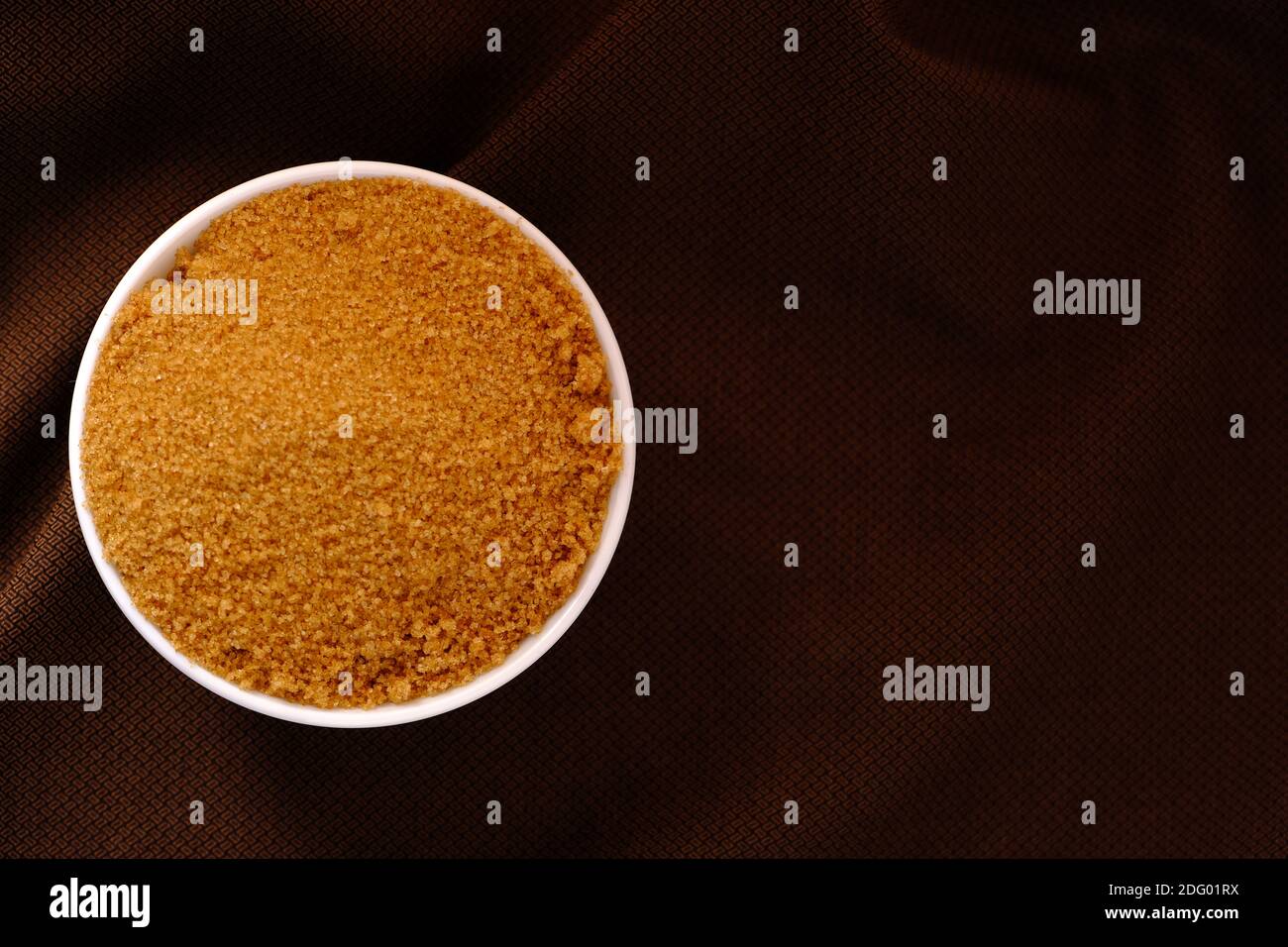 Brown Sugar Keramik Schüssel auf braunem Stoff Textur Hintergrund Stockfoto