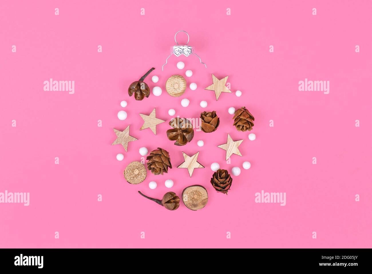 Saisonale Ornamente wie natürliche Hernlock Zapfen und Stick Scheiben mit Sterne und weiße Schneebälle bilden die Form der Weihnachtsbaumkugel Auf rosa Hintergrund Stockfoto
