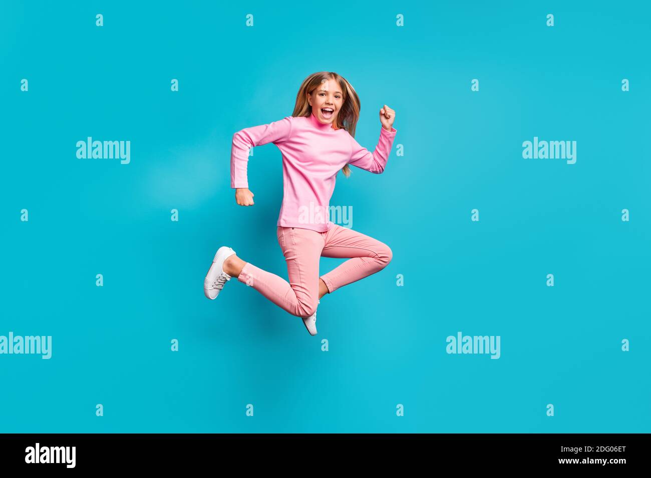 Profil in voller Länge Foto von schönen fröhlichen Teenager-Mädchen springen Tragen rosa Hosen Poloneck weißen Schuhe isoliert auf blauem Hintergrund Stockfoto