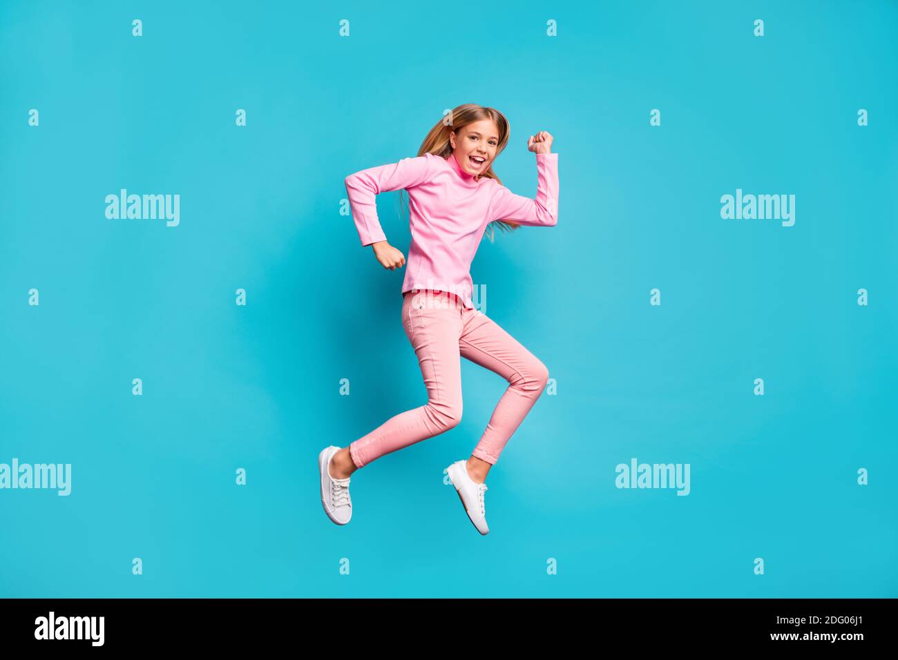 Profil in voller Länge Foto von niedlichen fröhlichen Mädchen springen tragen Rosa Hose Poloneck weiße Schuhe isoliert auf türkisfarbenem Hintergrund Stockfoto