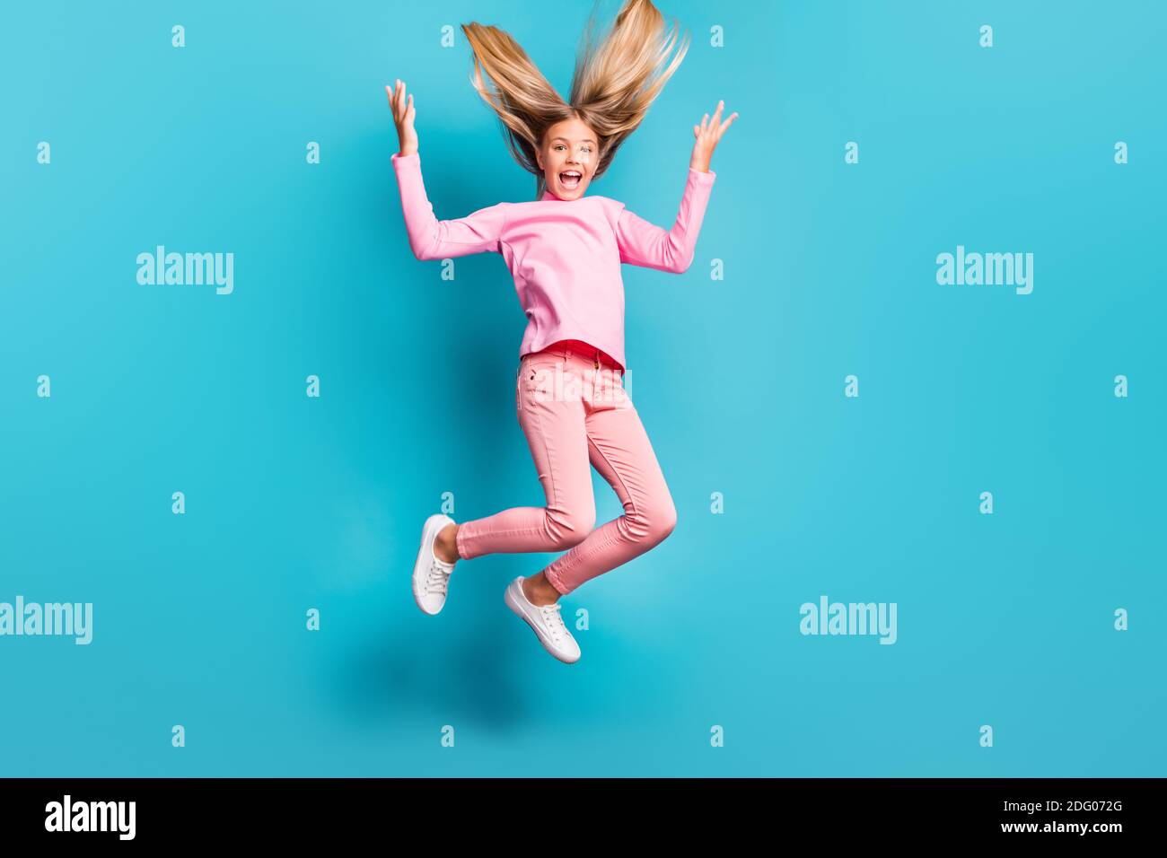 Foto in voller Größe von funky cool Teenager springen brüllen Haare Up tragen rosa Hose Poloneck weiß Schuhe isoliert auf teal Hintergrund Stockfoto