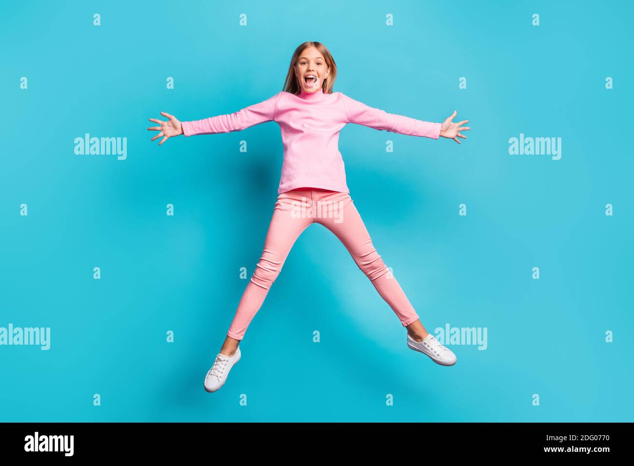 In voller Größe Foto von coolen funky ziemlich Teenager springen wie Star yell tragen rosa Hose Poloneck weiß Schuhe isoliert auf blaugrün Hintergrund Stockfoto