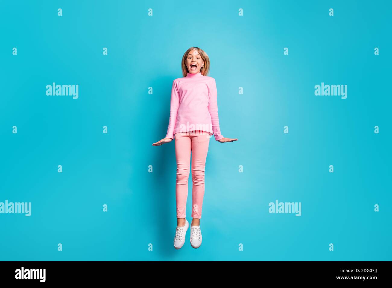 In voller Größe Foto von cool erstaunt schön teen Mädchen springen Air tragen rosa Hose Poloneck weiß Schuhe isoliert auf blaugrün Hintergrund Stockfoto