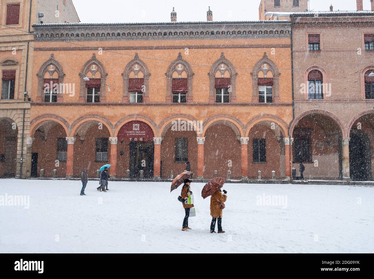 Menschen unter Sonnenschirmen im fallenden Schnee auf der Piazza di Santo Stefano, Bologna, Italien. Stockfoto