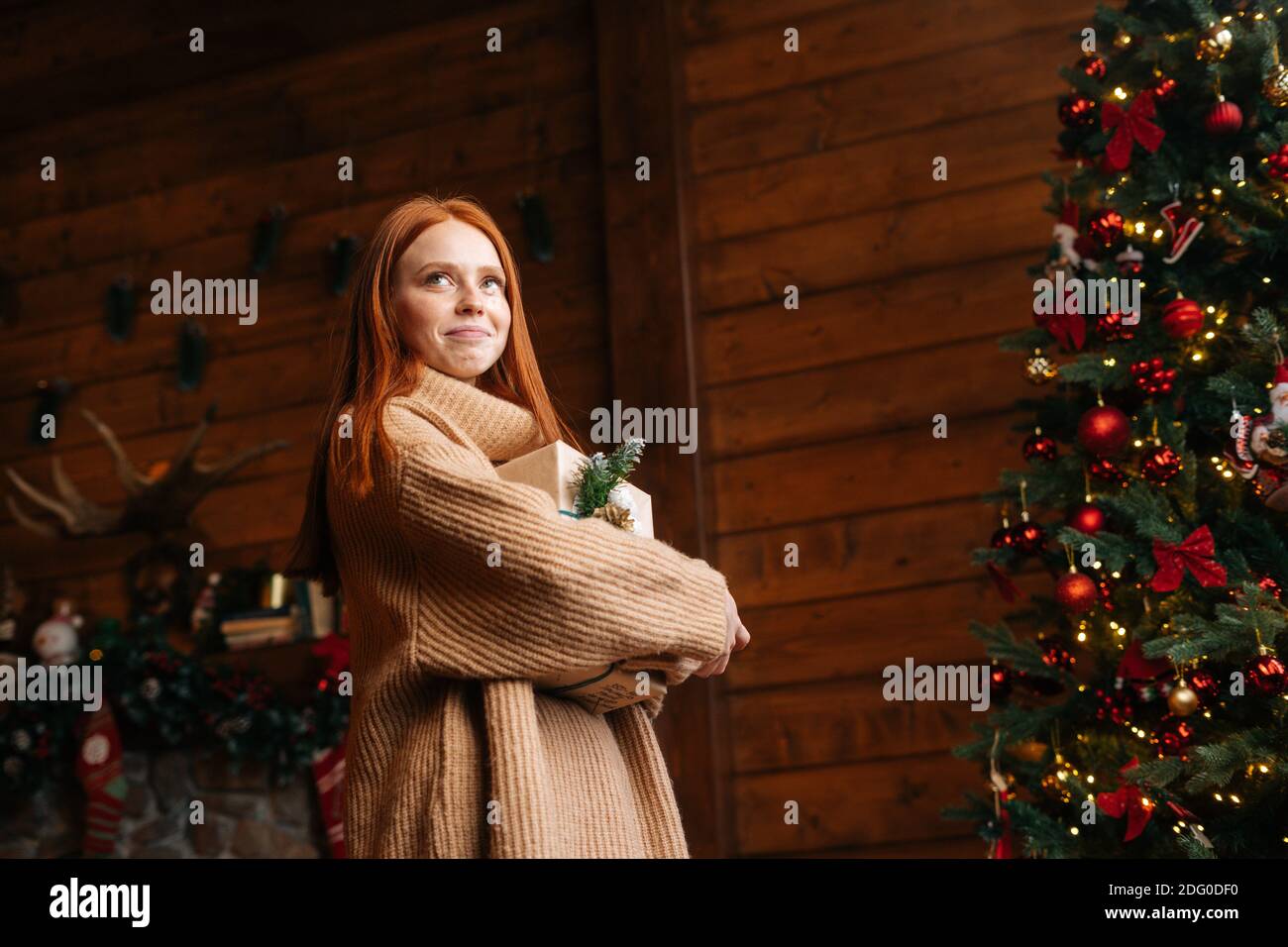 Low-Winkel Schuss fröhlich Rotschopf junge Frau hält schöne Weihnachten Geschenkbox. Stockfoto