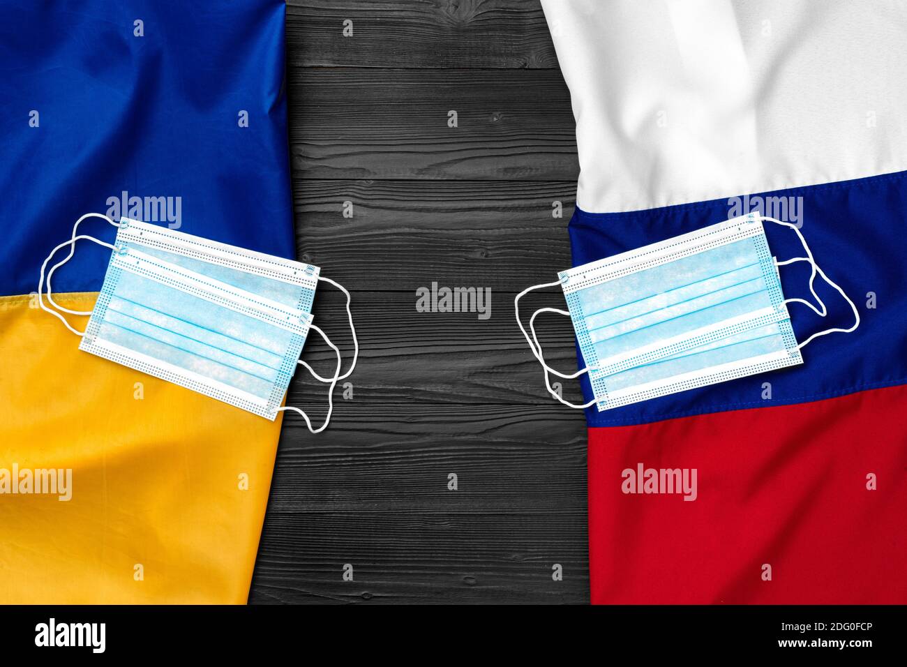 Flaggen von Russland und der Ukraine auf hölzernen Hintergrund mit medizinischen Masken Stockfoto