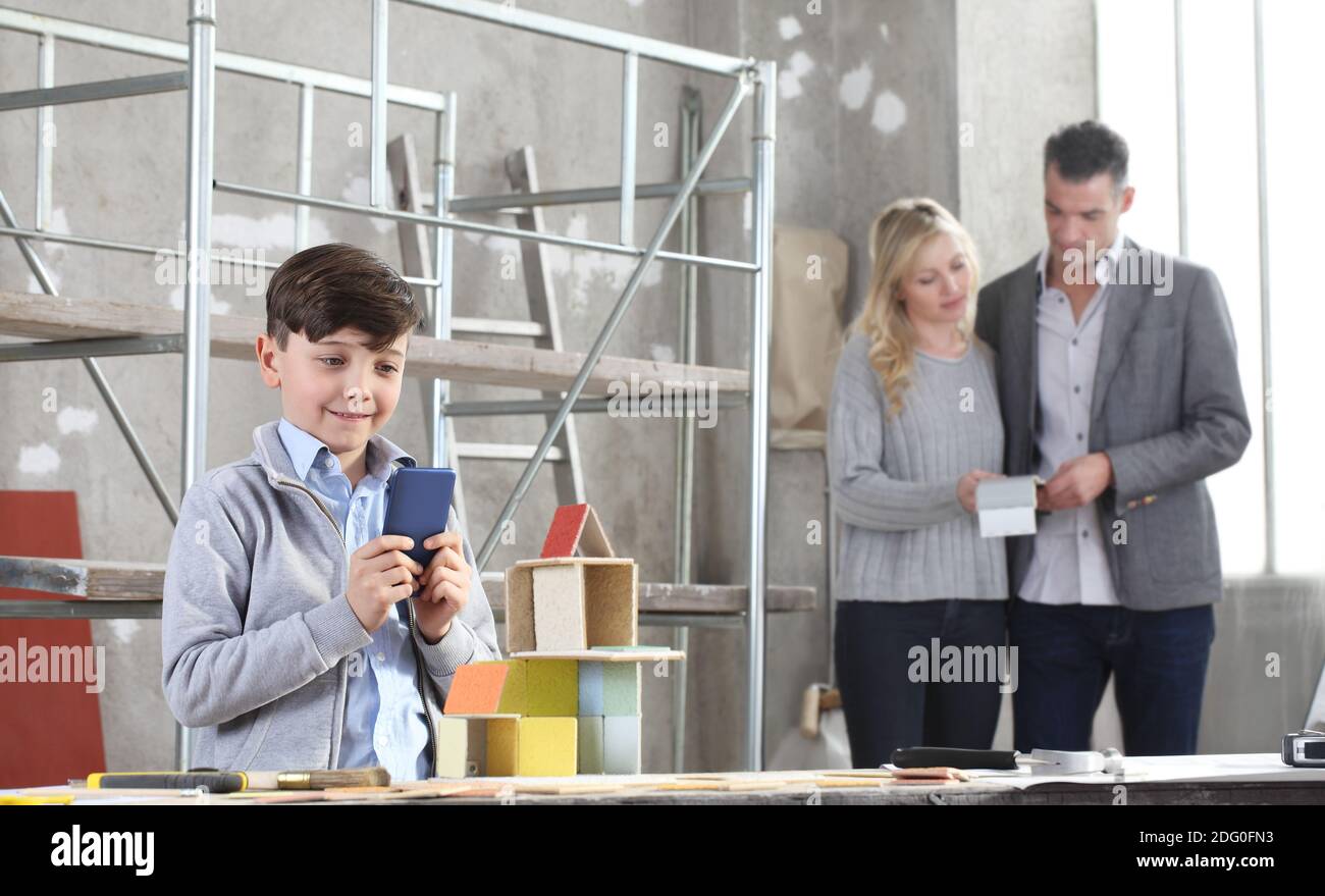 Glückliche Kinder mit Handy spielen Bau eines Hauses mit Baumodellen. Seine Familie wählt, wie man dekorateat. Haus kaufen und Gebäude Ziel Stockfoto