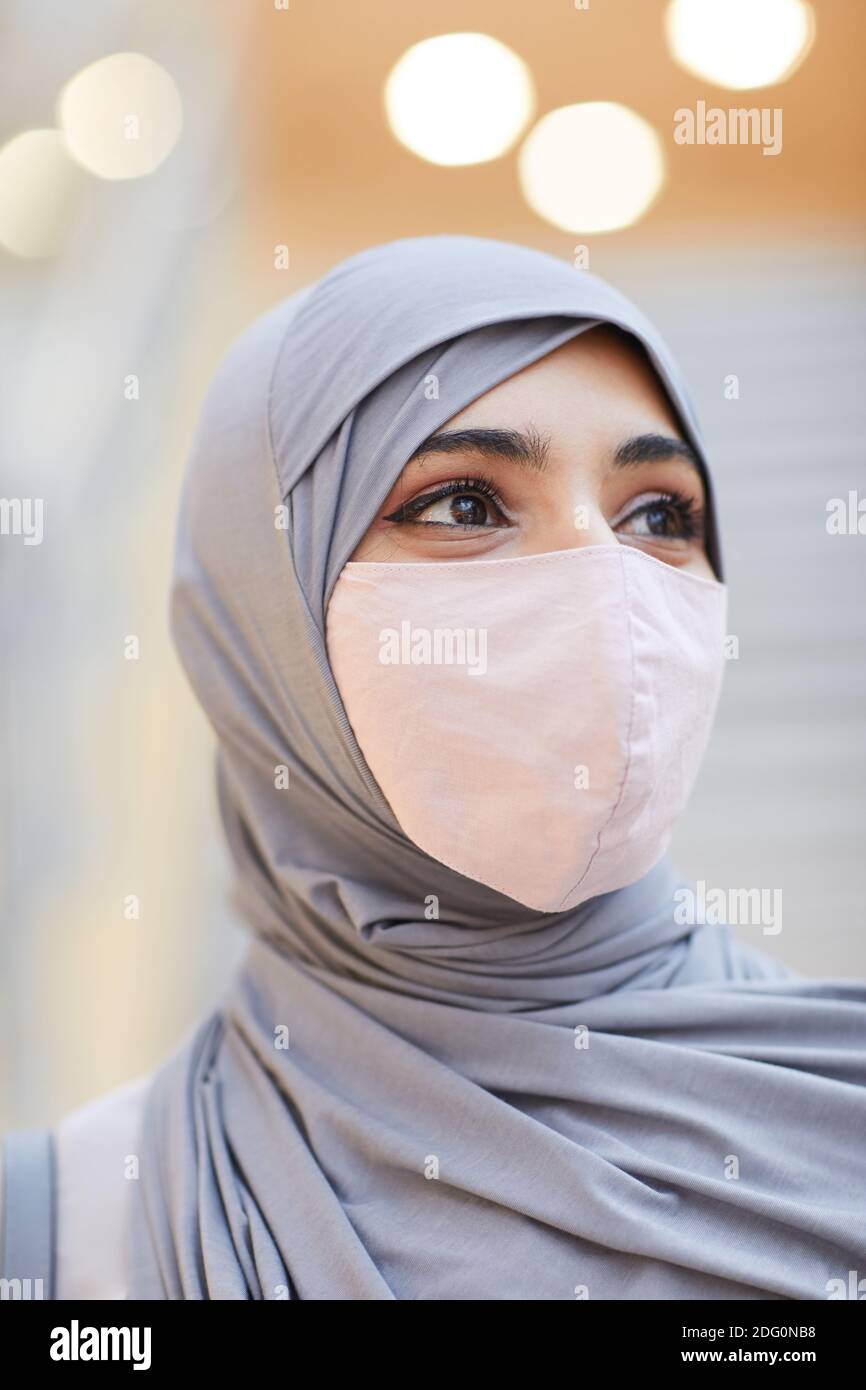 Vertikale Nahaufnahme Porträt der modernen Nahost-Frau trägt Maske Und Kopftuch beim Posen im Einkaufszentrum Stockfoto