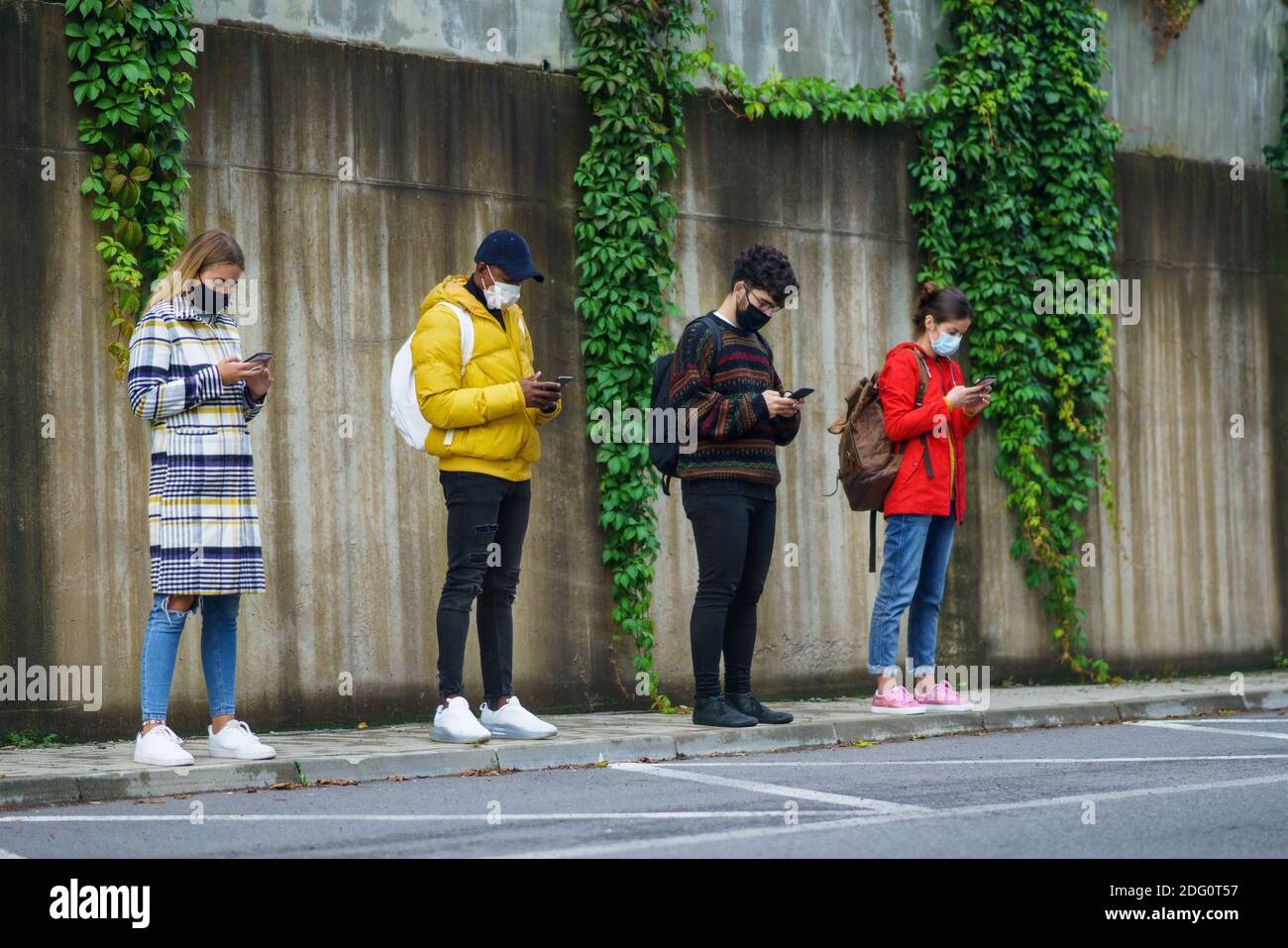 Junge Menschen mit Smartphone im Freien in der Stadt. Coronavirus und sicheres Entfernungskonzept. Stockfoto