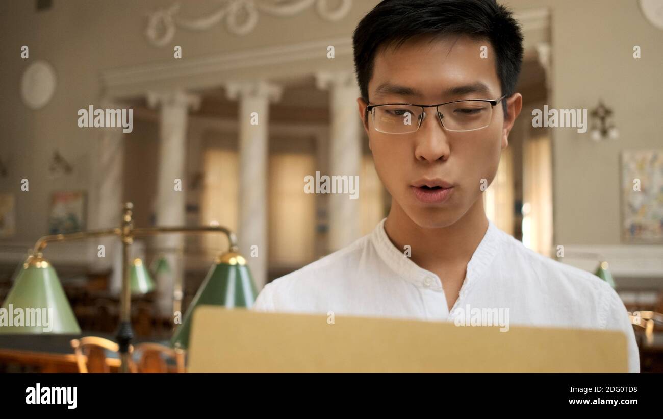 Asiatische Student aufregend öffnen Umschlag mit Prüfungsergebnissen in der Universität Stockfoto