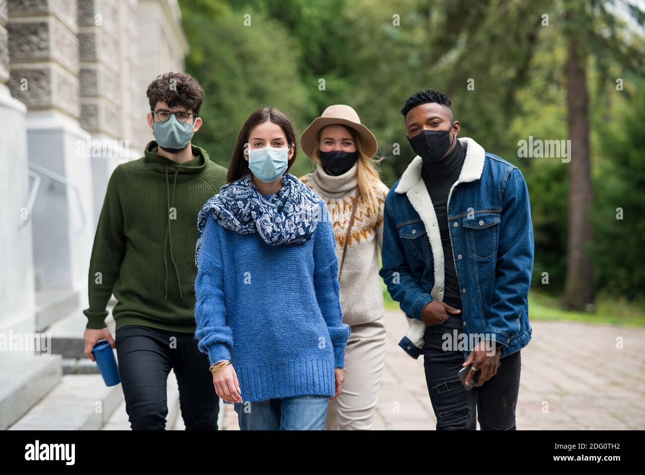 Gruppe von jungen Menschen mit Gesichtsmaske im Freien in der Stadt, zu Fuß. Coronavirus-Konzept. Stockfoto