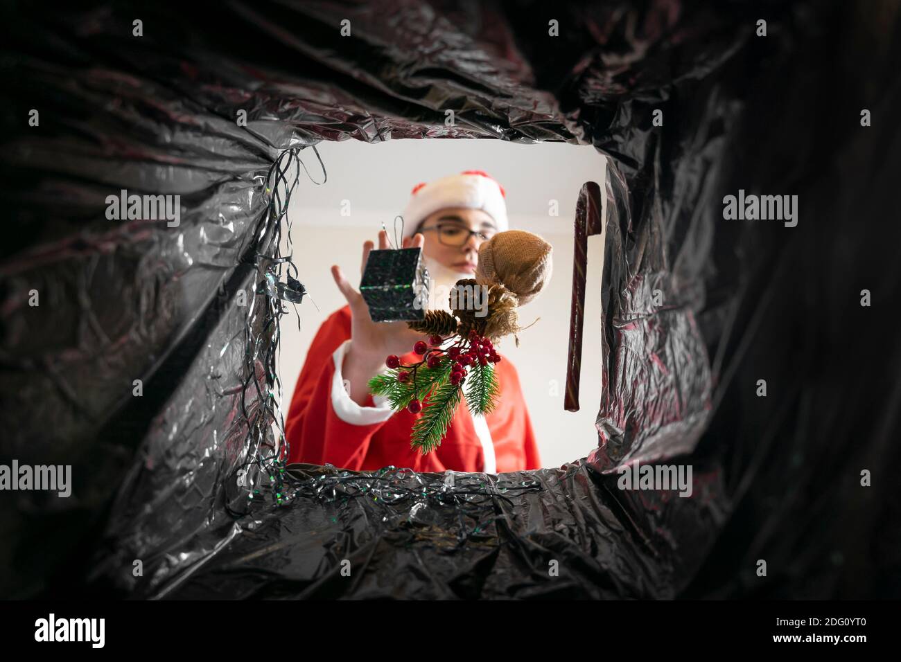 Santa wirft Geschenke und Weihnachtsdekorationen in den Müll. Blick aus dem Müllcontainer. Stockfoto