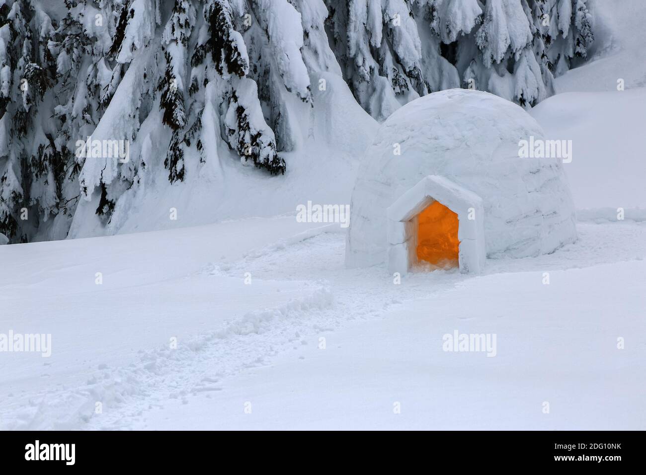 Der breite Weg führt zum verschneiten Iglu. Winterlandschaft in den Bergen. Haus mit Licht. Lage Ort der Karpaten, Ukraine, Europa. Stockfoto