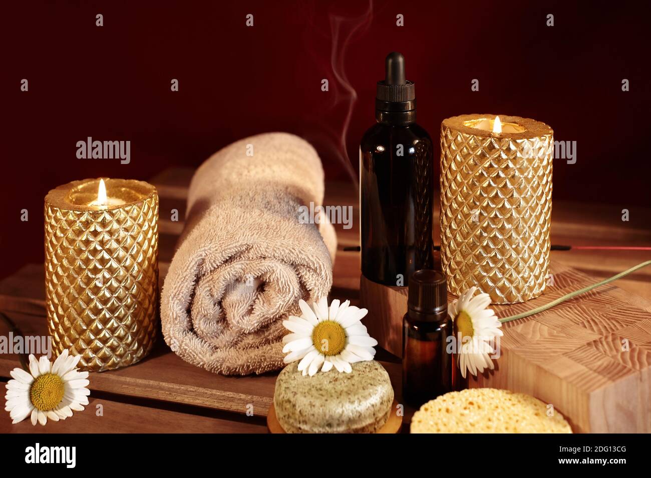 Wunderschöne Spa-Komposition. Aromatherapie mit Kräuteröl, Naturseife und Goldkerzen. Entspannungsfarbe und wärmende Handtücher auf Holzhintergrund Stockfoto