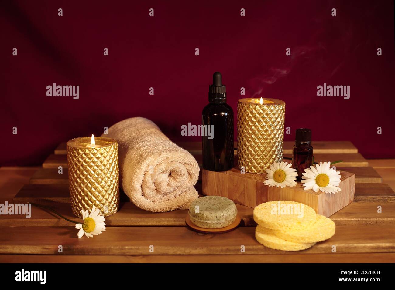 Wunderschöne Spa-Komposition. Aromatherapie mit Kräuteröl, Naturseife und Goldkerzen. Entspannungsfarbe und wärmende Handtücher auf Holzhintergrund Stockfoto